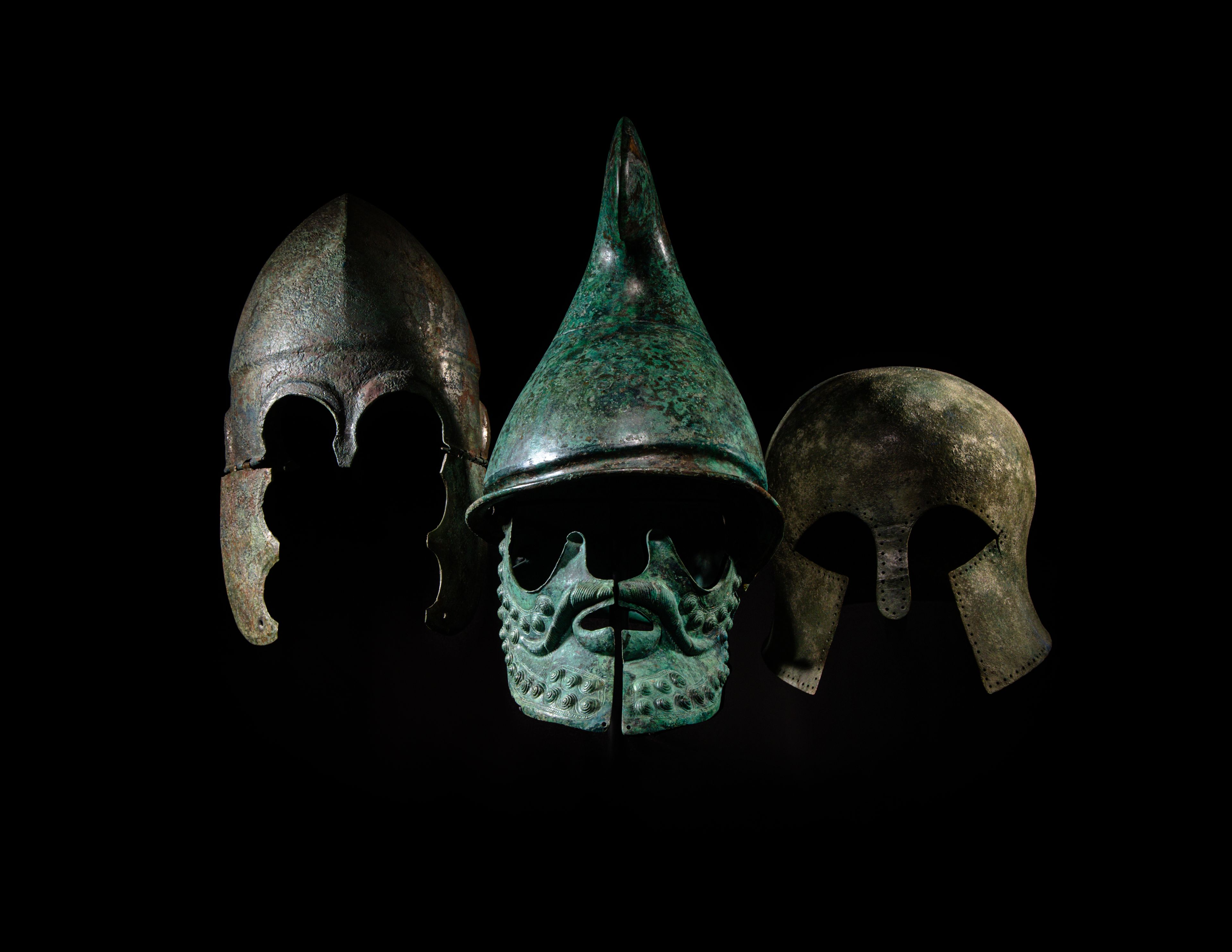 A Greek Tinned-Bronze Chalcidian Helmet (BC 500-301, Estimate: $15,000 – 25,000), Greek Bronze Phrygian Helmet (Circa 350-300 B.C., Estimate: $80,000 – 120,000), and a Greek Bronze Corinthian Helmet (Circa 6th Century B.C., Estimate: $60,000 – 80,000)