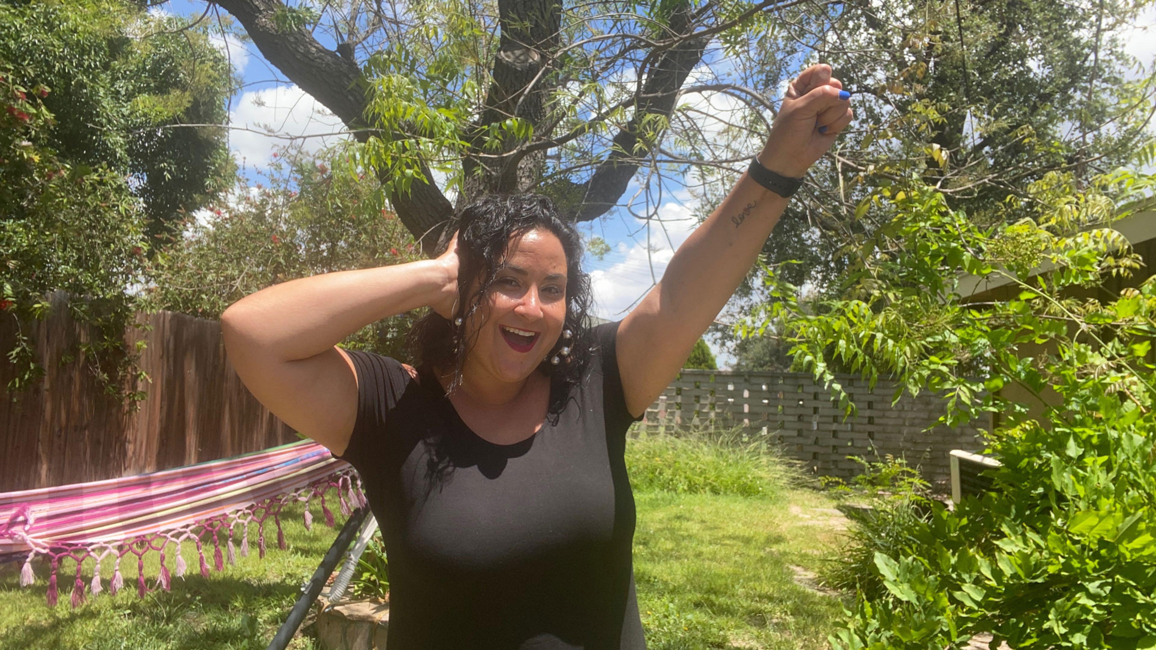 A woman in a leafy garden making the Deaf Power sign