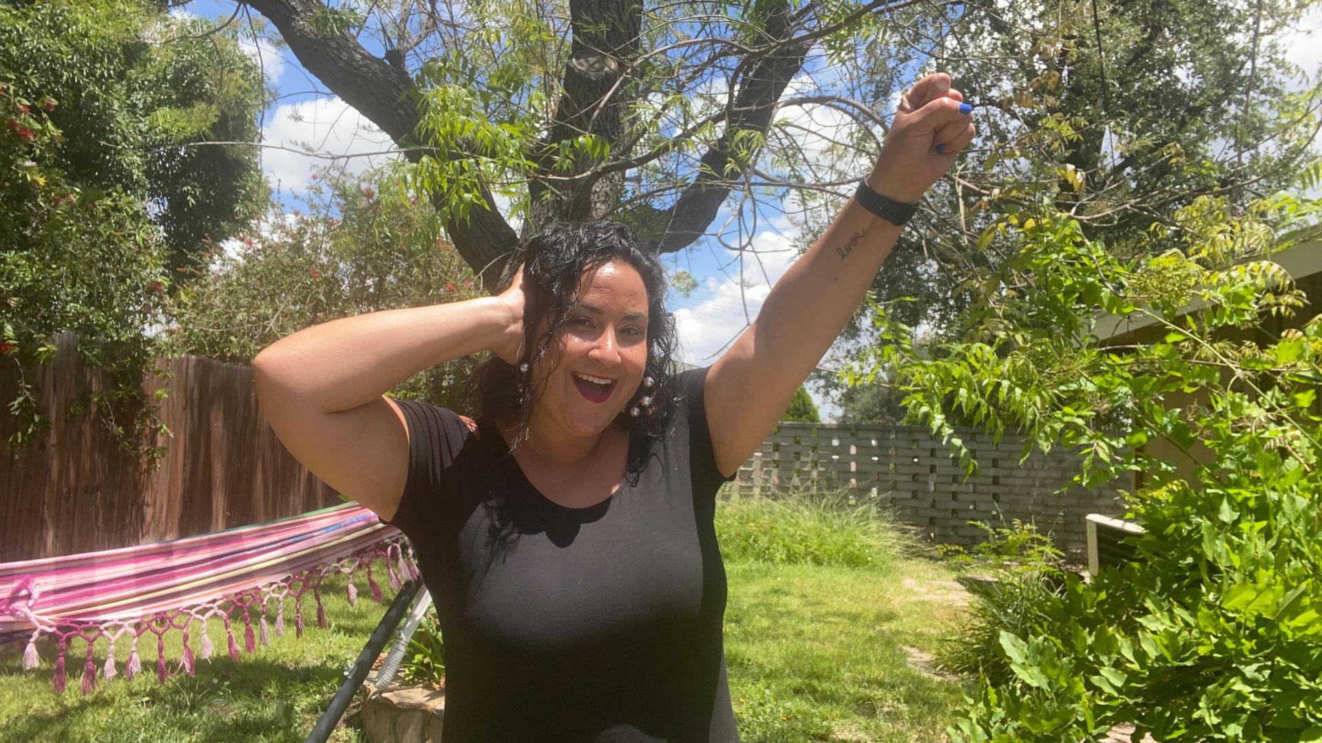 A woman in a leafy garden making the Deaf Power sign