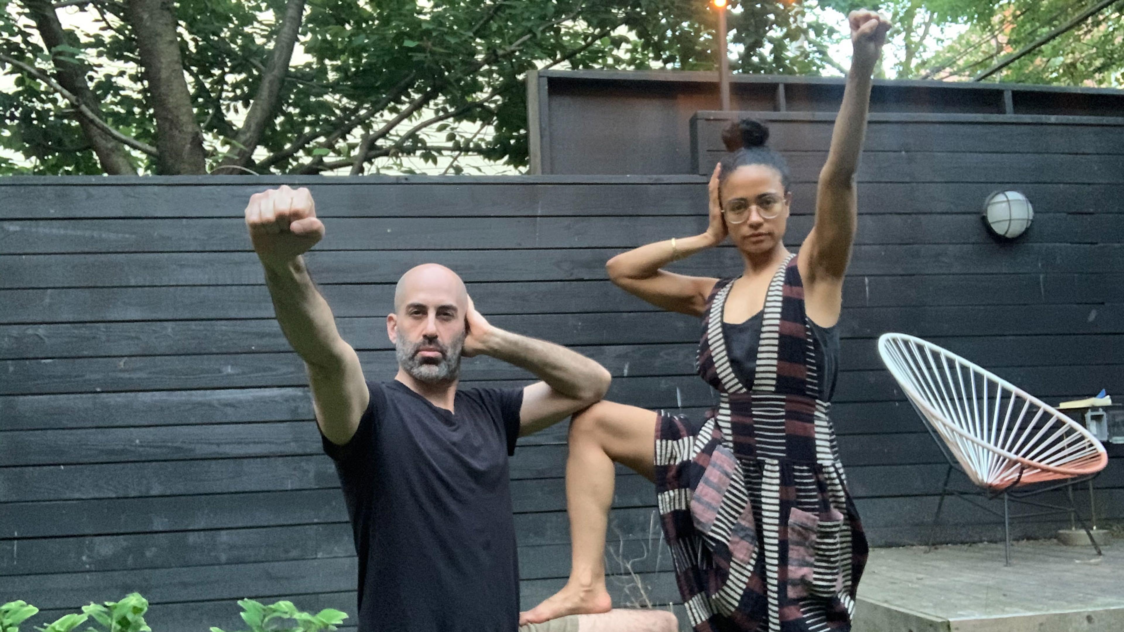 A man and a woman in a backyard making the Deaf Power sign together