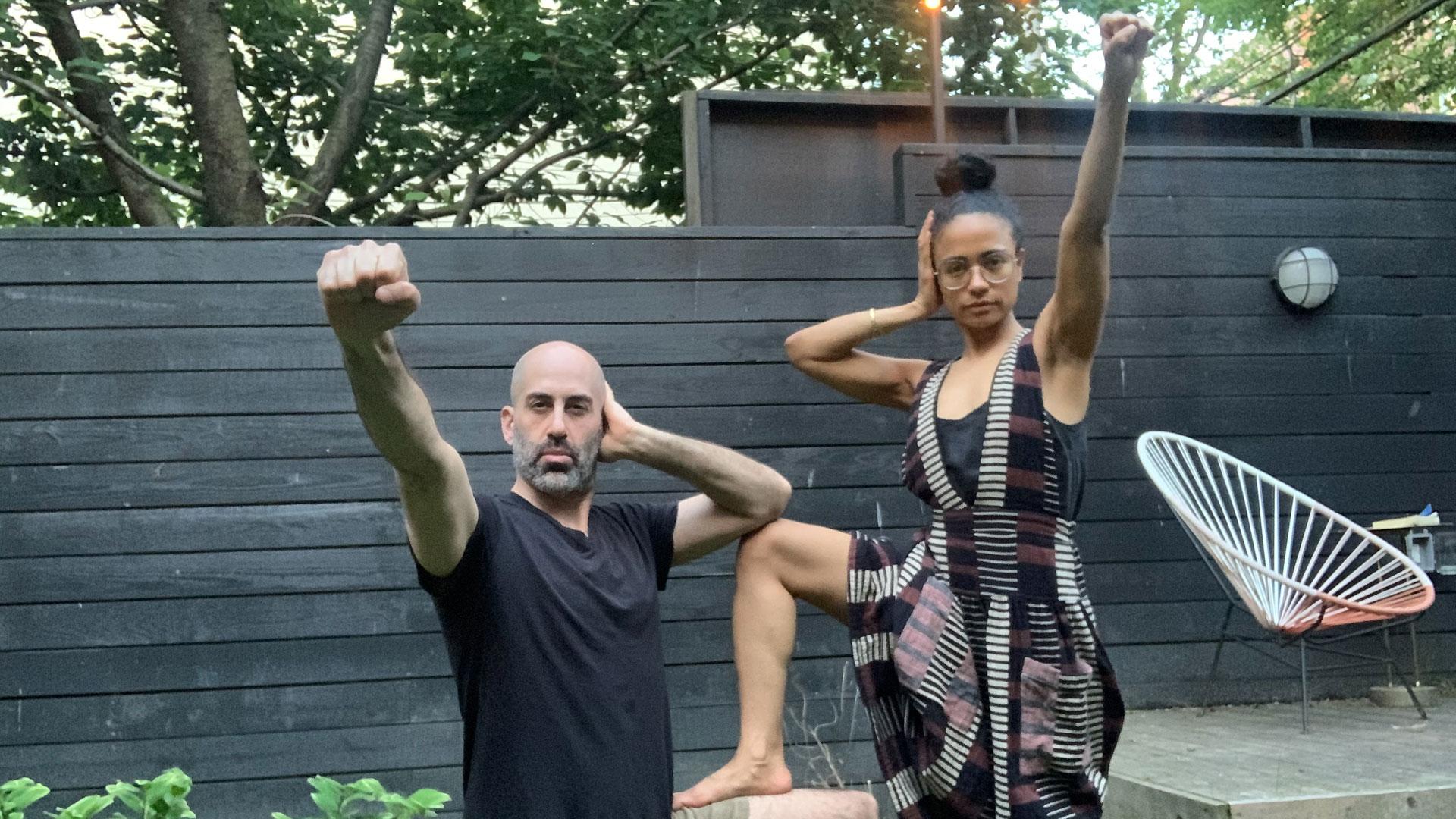 A man and a woman in a backyard making the Deaf Power sign together