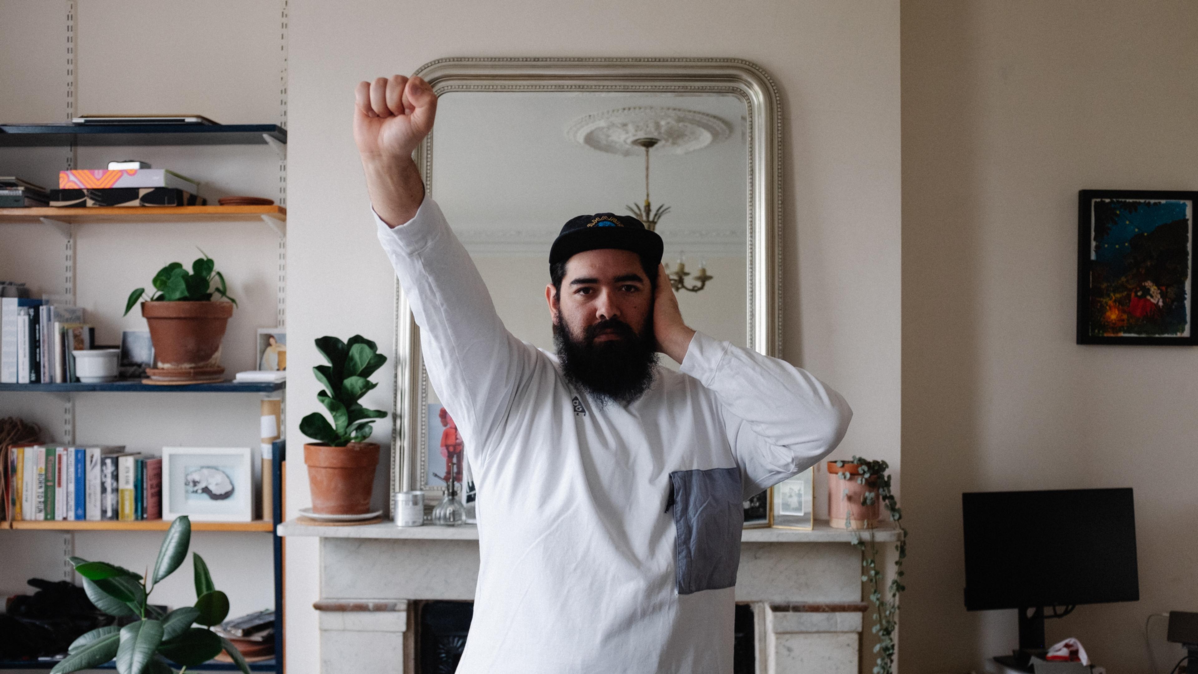 A bearded man in a living room making the Deaf Power sign