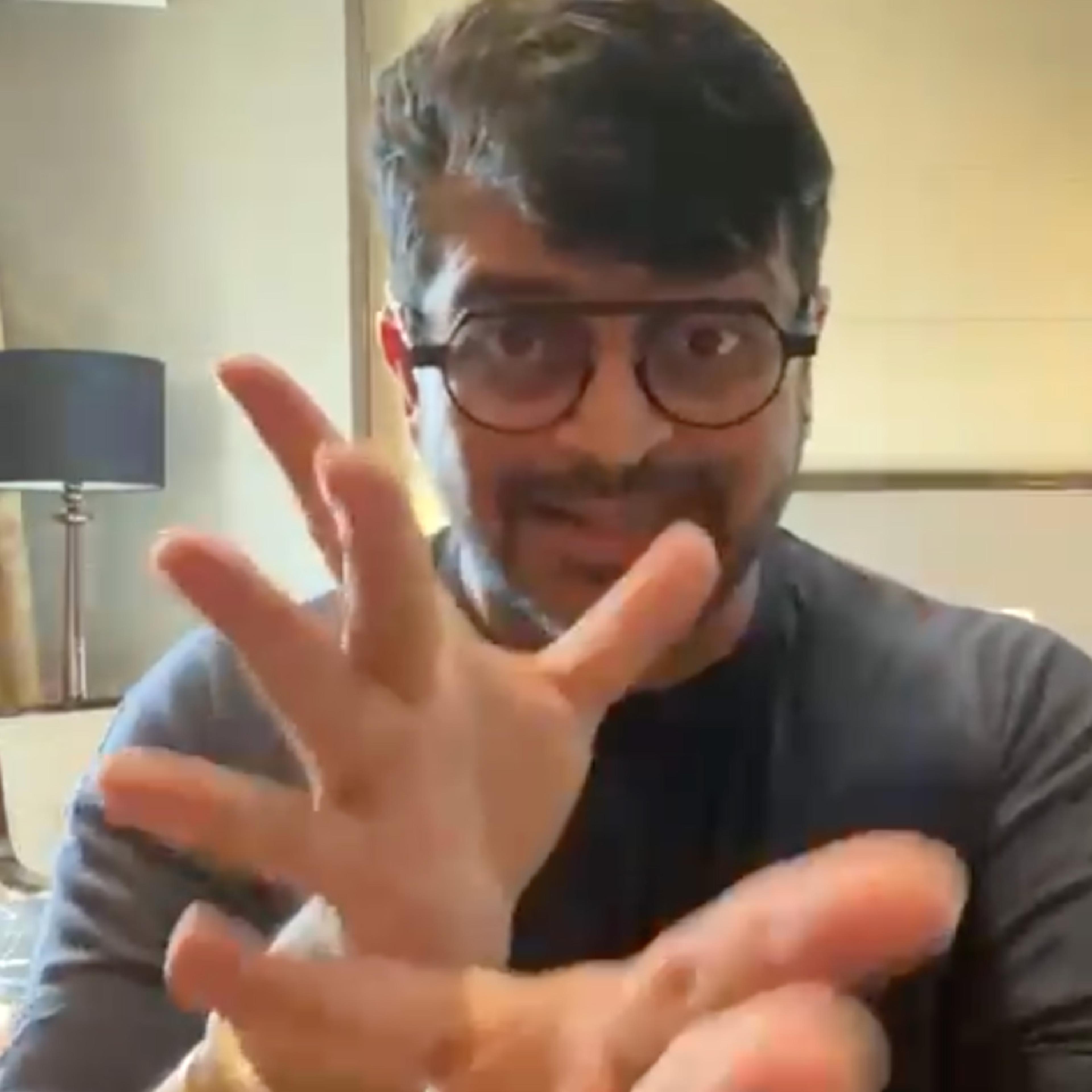 A man in glasses signing close to the camera