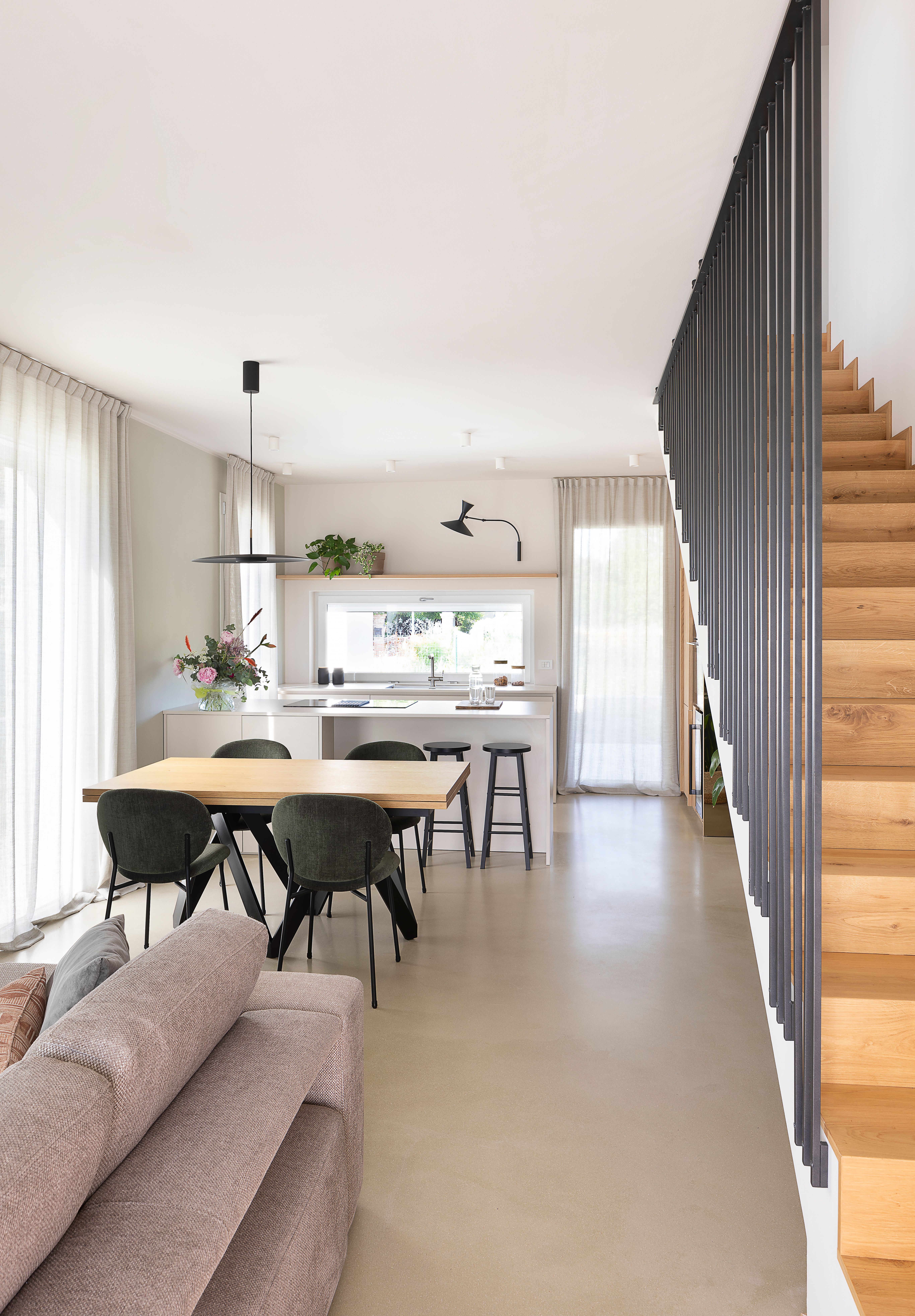 foto a colori di una sala con scale, divano, tavolo da pranzo e cucina 