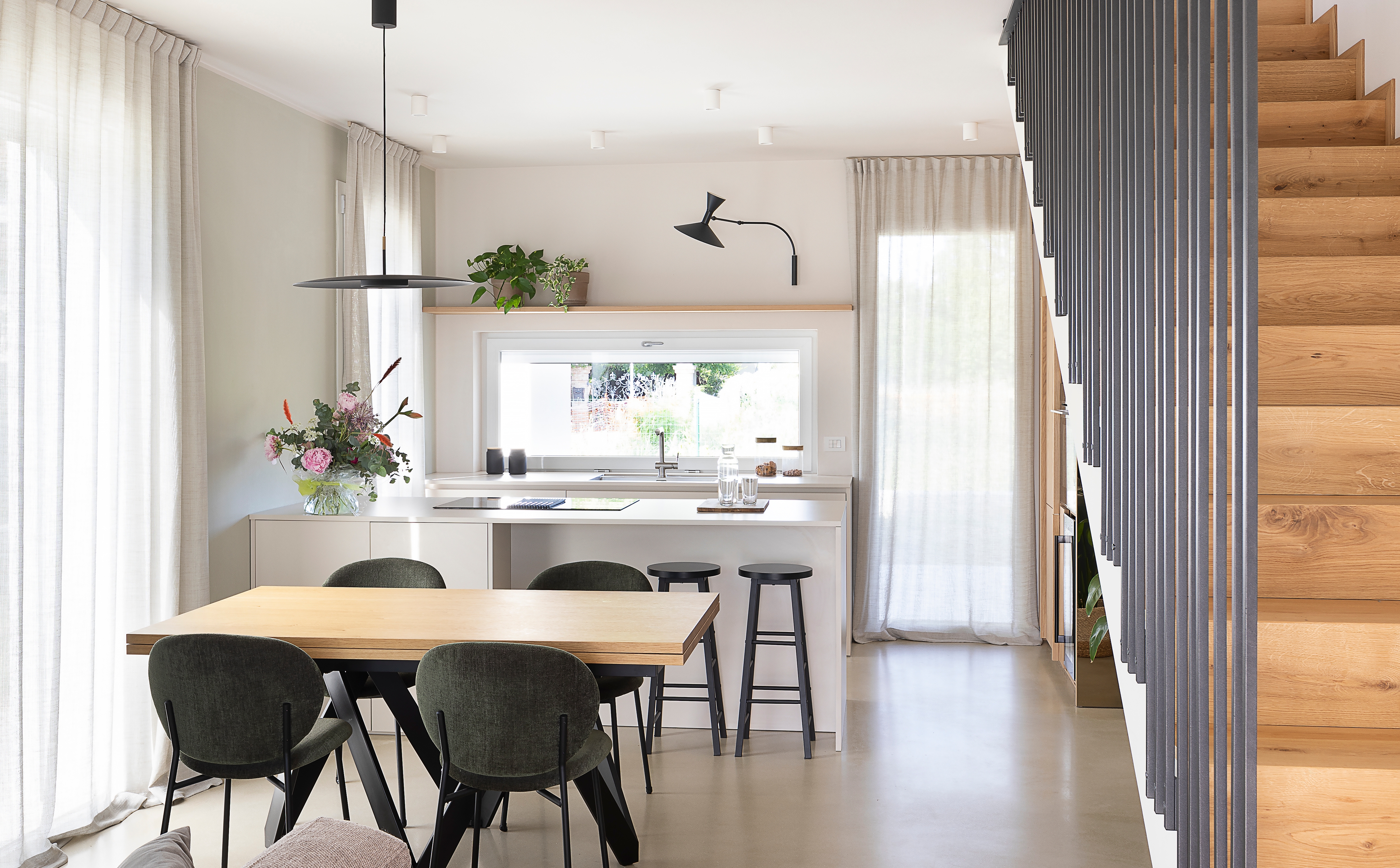 foto a colori di una sala con scale, divano, tavolo da pranzo e cucina