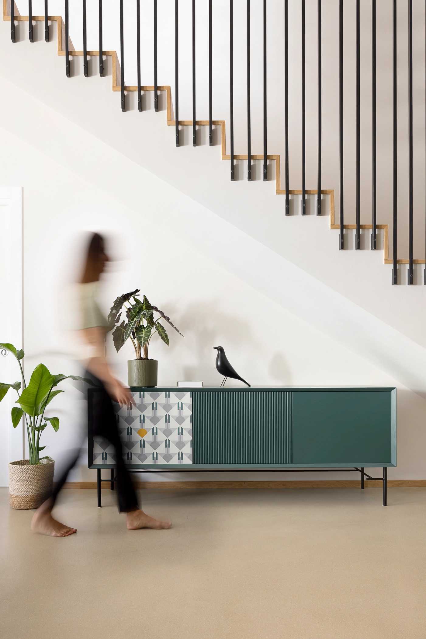 foto a colori di una madia color ottanio con una persona in movimento