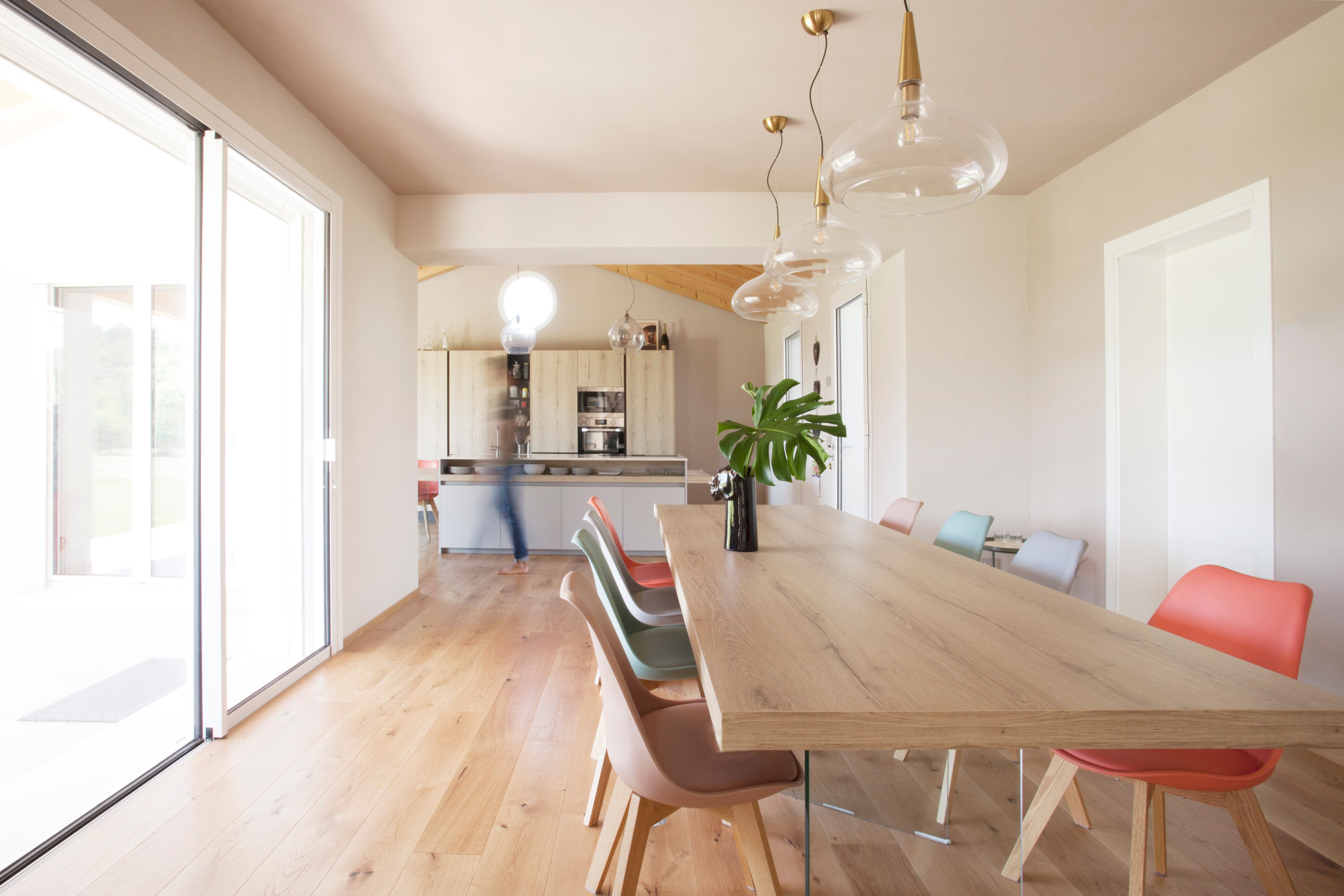 una stanza con un tavolo in legno e alcune sedie colorate al centro