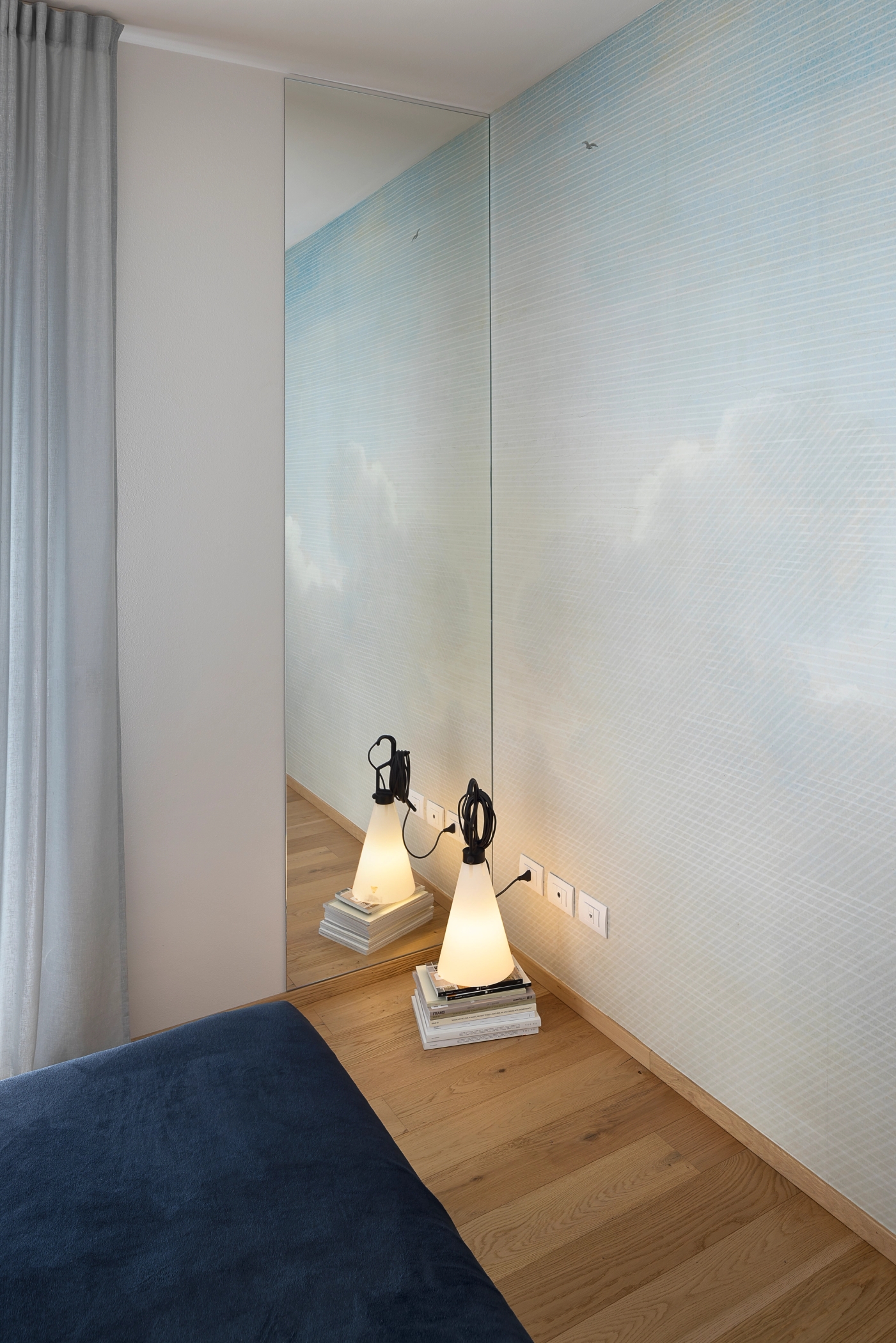 foto a colori di una parete con carta da parati con nuvole e lampada di design