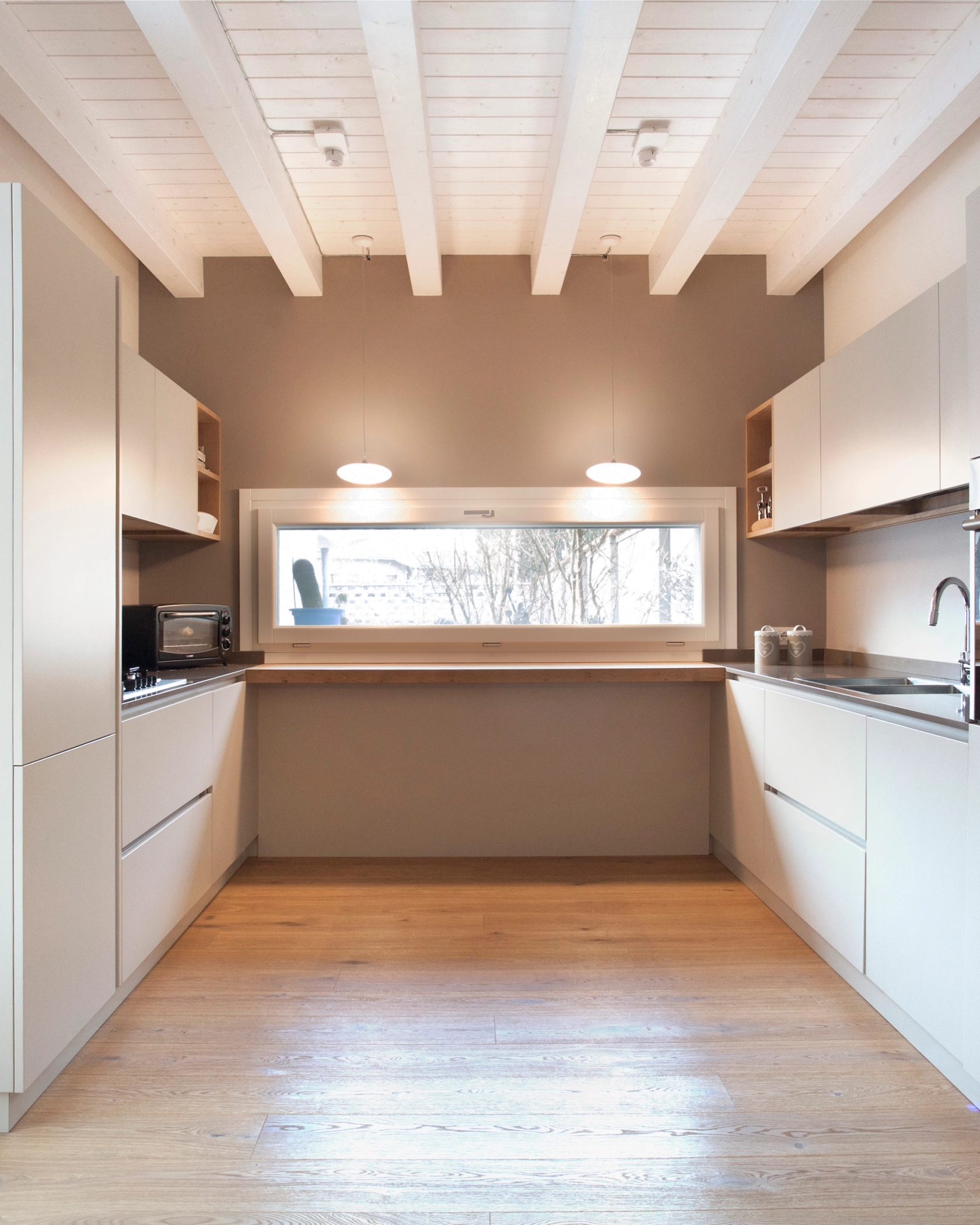 foto a colori di una cucina in legno bianco e soffitto trvato bianco