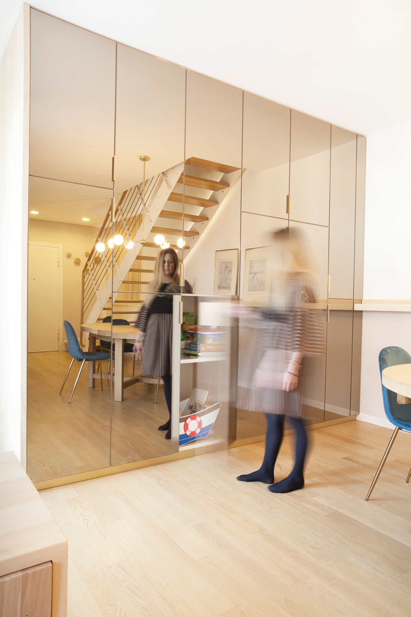 foto a colori con donna che apre anta parete specchiata