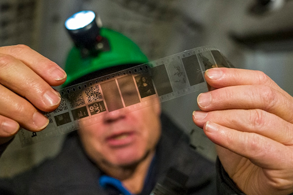 A man holding a piqlFilm strip inside a cave.