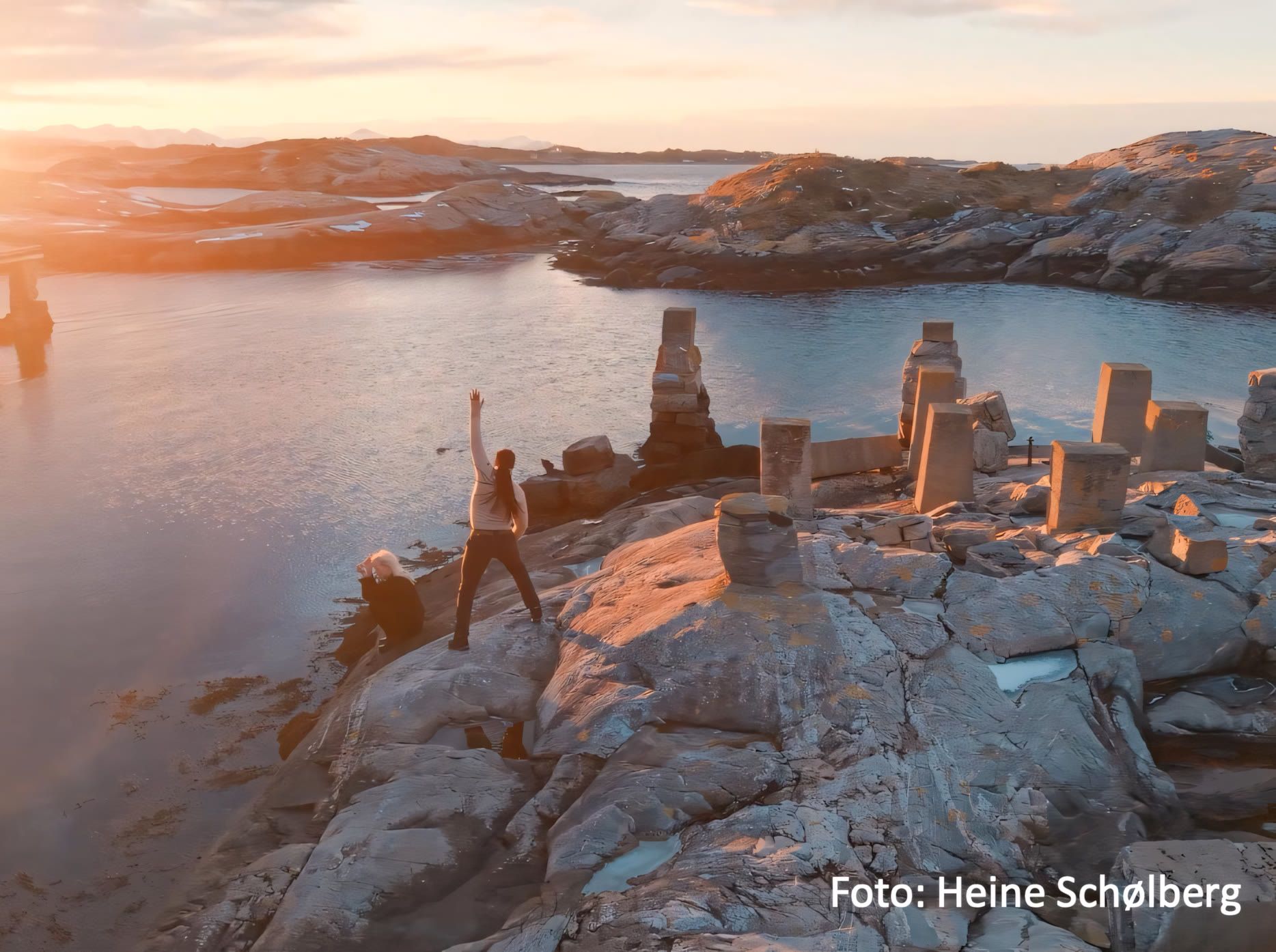 A person standing on the rocky coastline of Kristiansund, arms outstretched towards the sea
