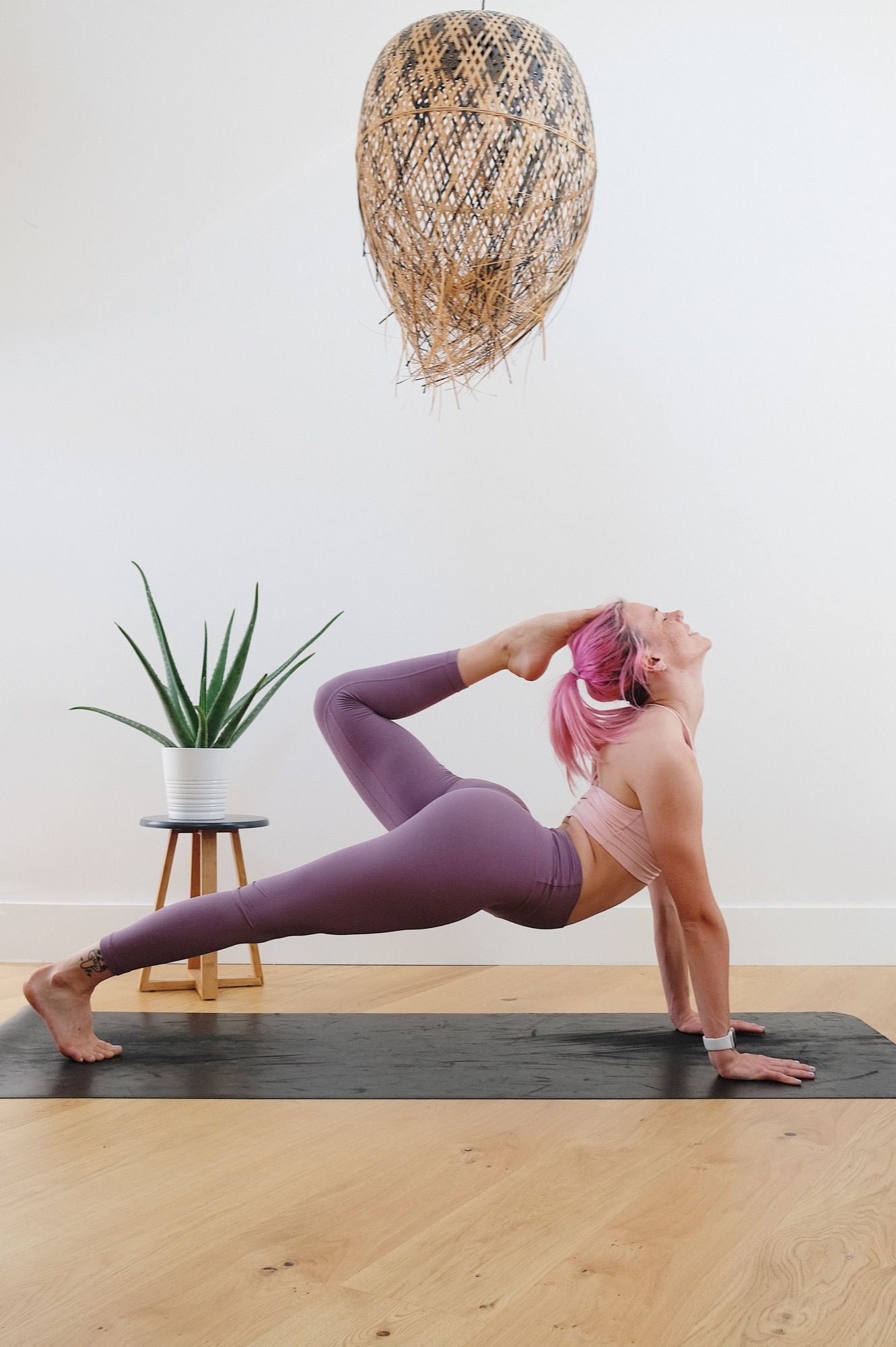 Woman in a low lunge with a plant in the background