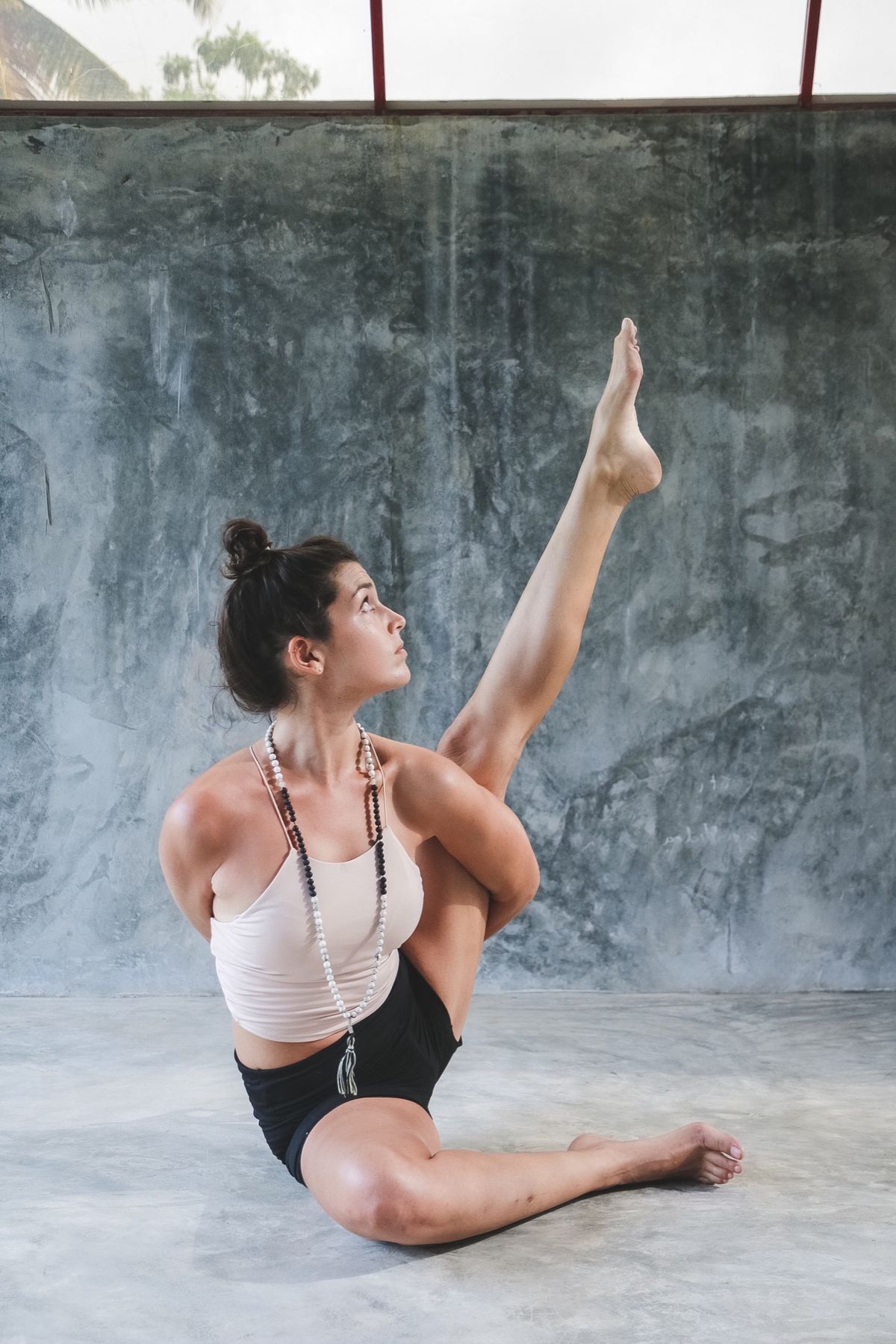 Yoga teacher holding a seated leg extension