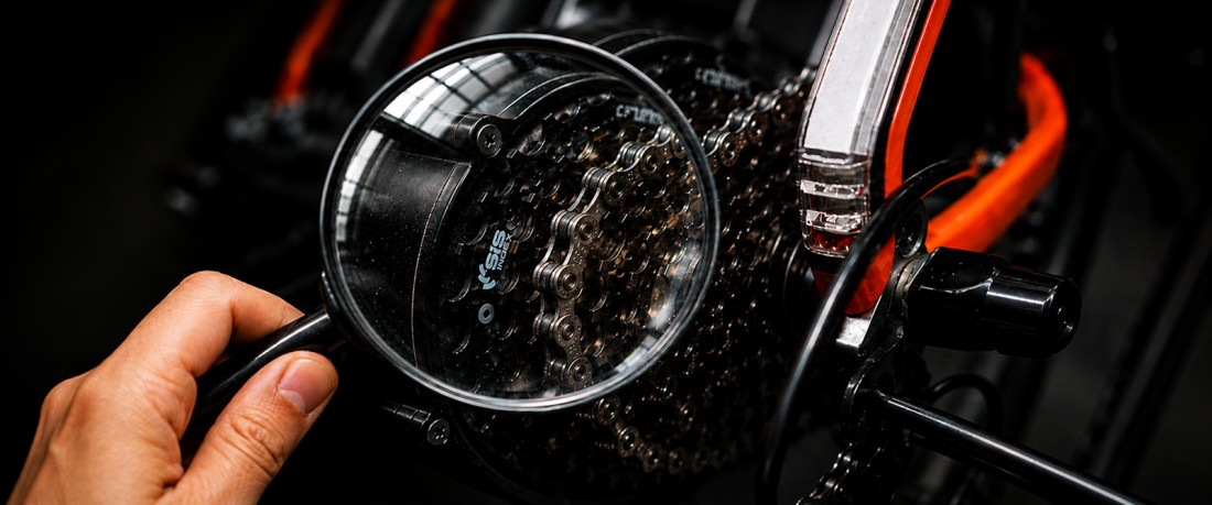 Magnifying glass inspecting the chain and gears of an electric bike before buying an eBike