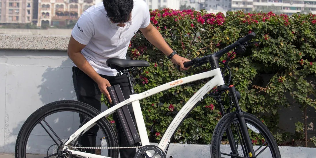 Rider fitting a removable battery into a white NINE09 eBike before a long electric bike ride
