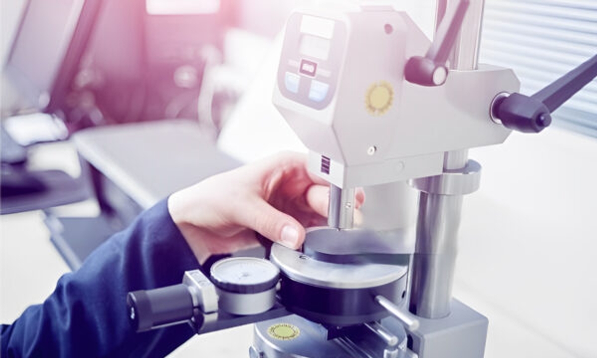 Person conducting hardness testing using a machine.