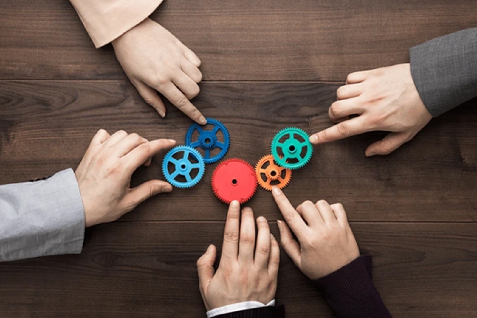 Photo de mains assemblant des engrenages colorés imbriqués sur une table