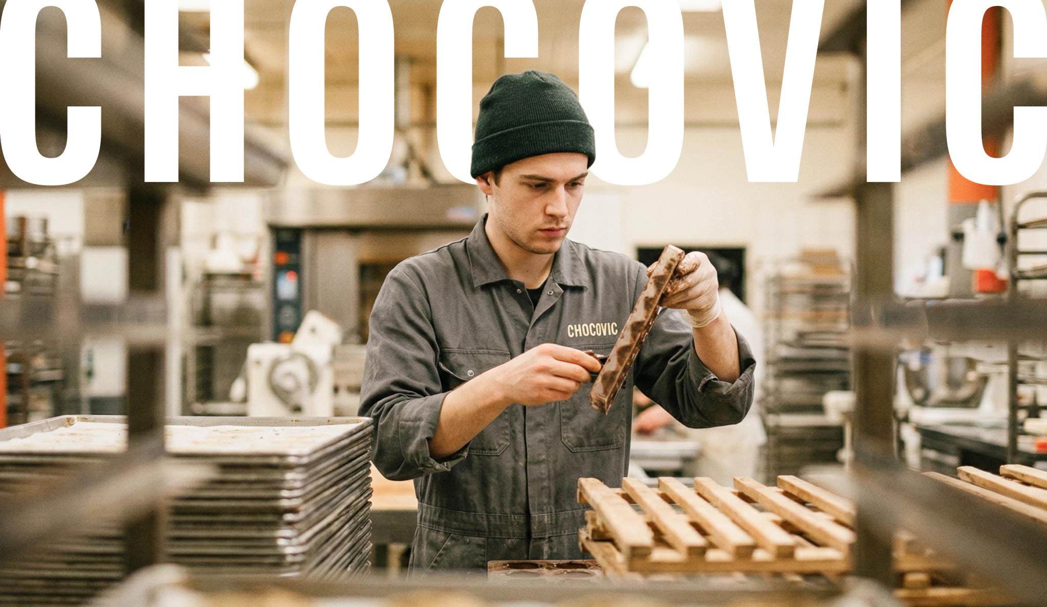 Chocovic — a baker in a Chocovic work jacket inspecting a chocolate bar in the workshop