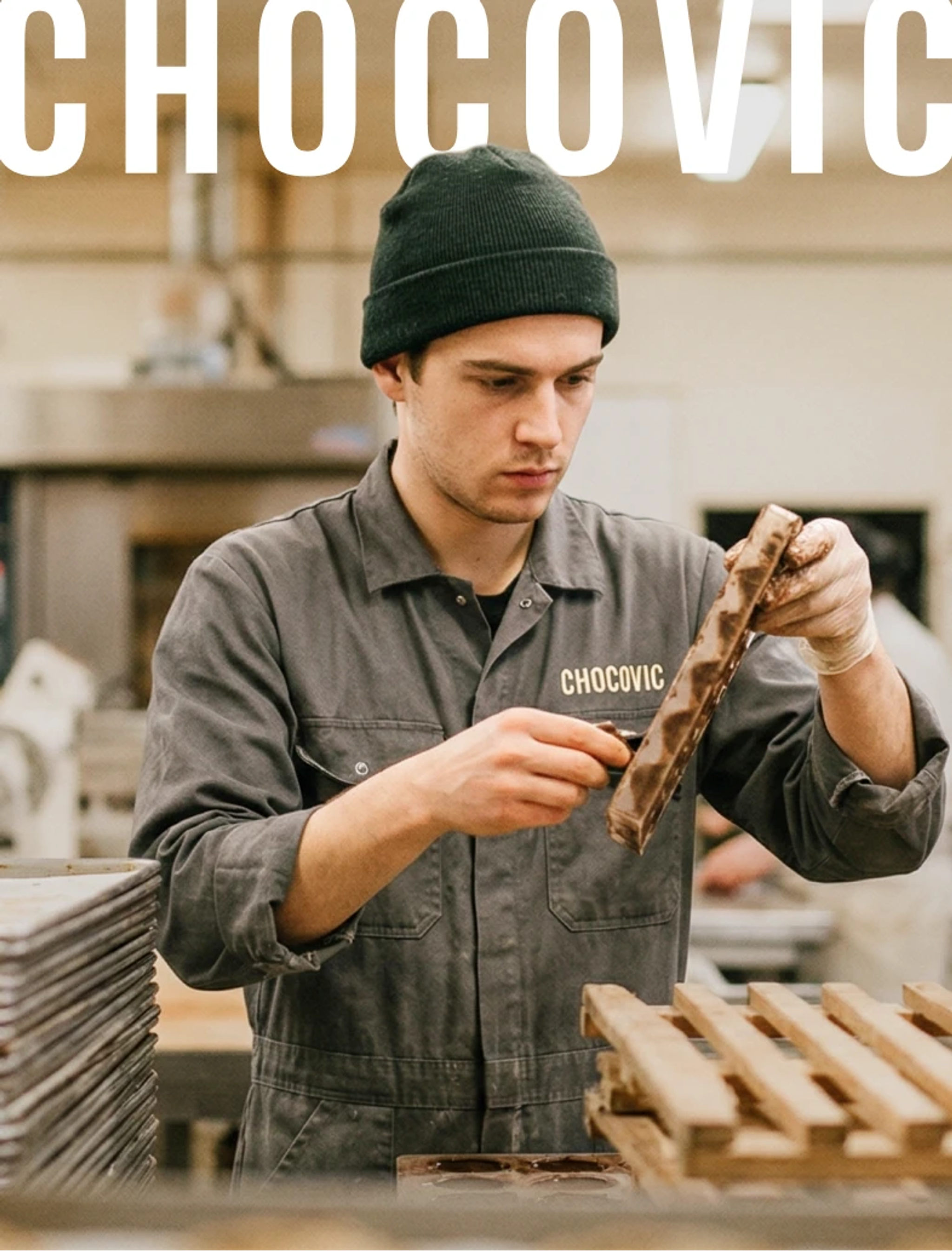Chocovic — a baker in a Chocovic work jacket inspecting a chocolate bar in the workshop