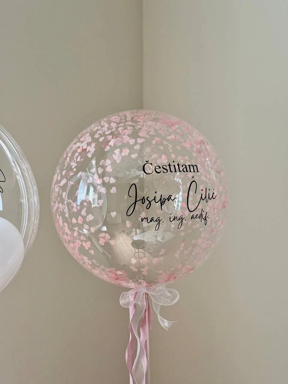 Prozirni balon s ružičastim konfetima i čestitkom magistrici.