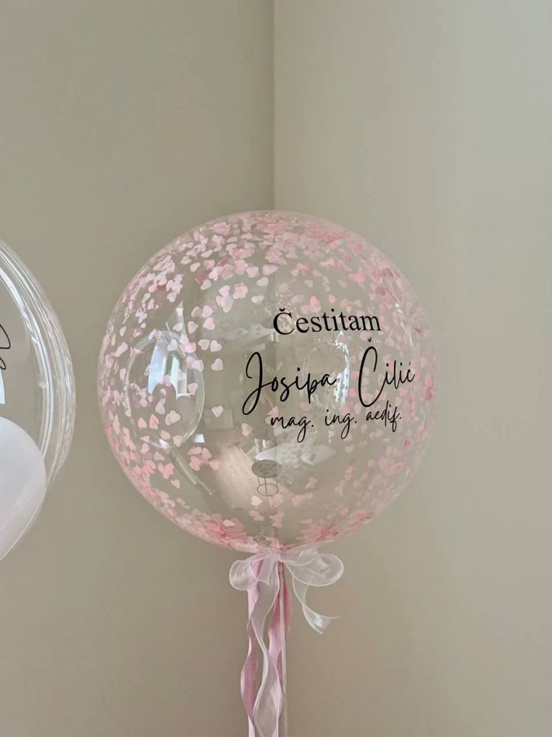 Prozirni balon s ružičastim konfetima i čestitkom magistrici.