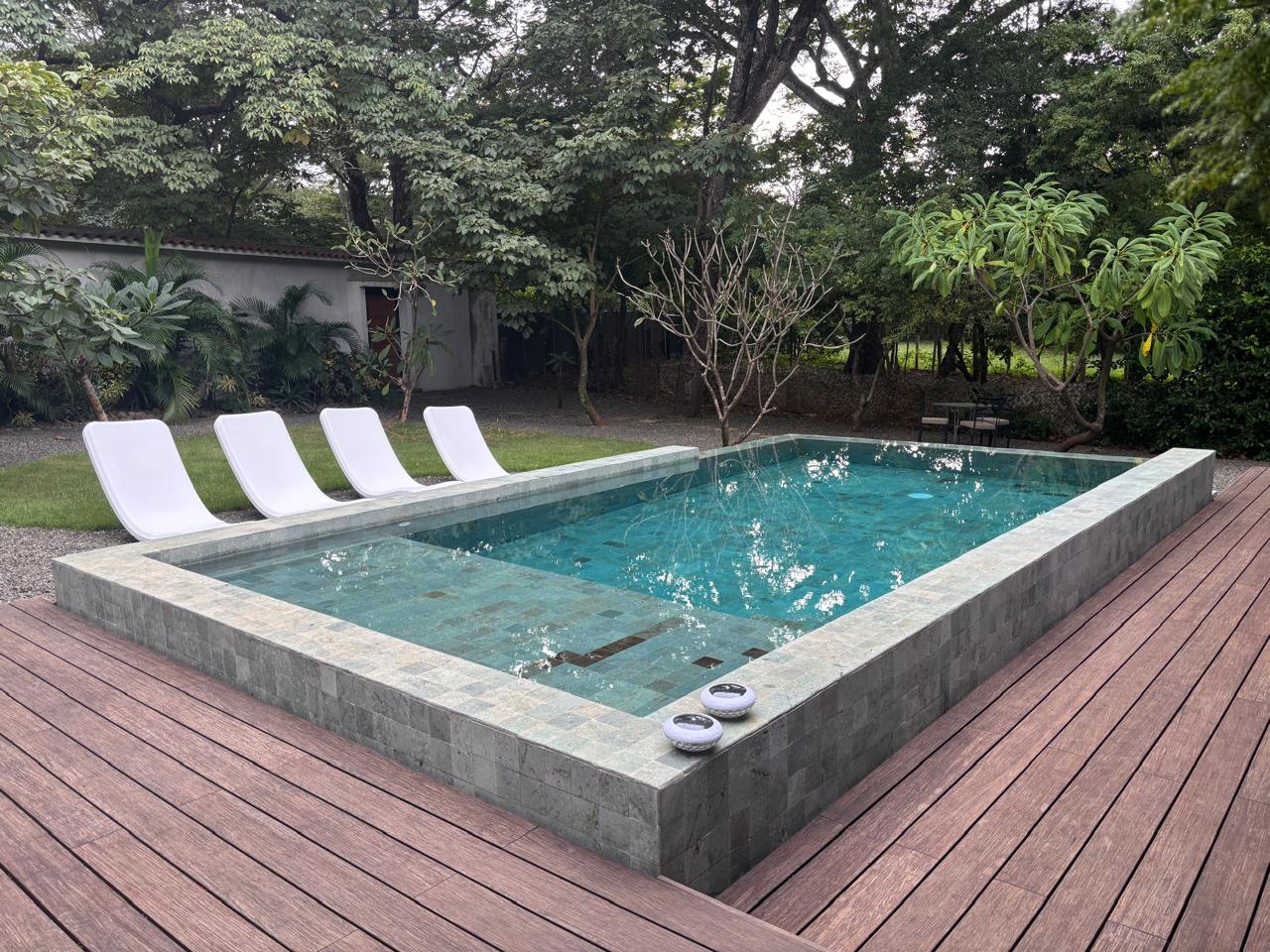 Piscina elevada en piedra verde con deck