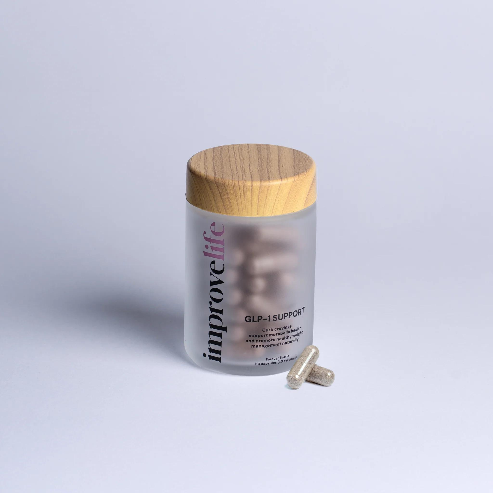 Frosted bottle of Improve Life GLP-1 Support capsules with a wooden lid, and two capsules resting beside it.