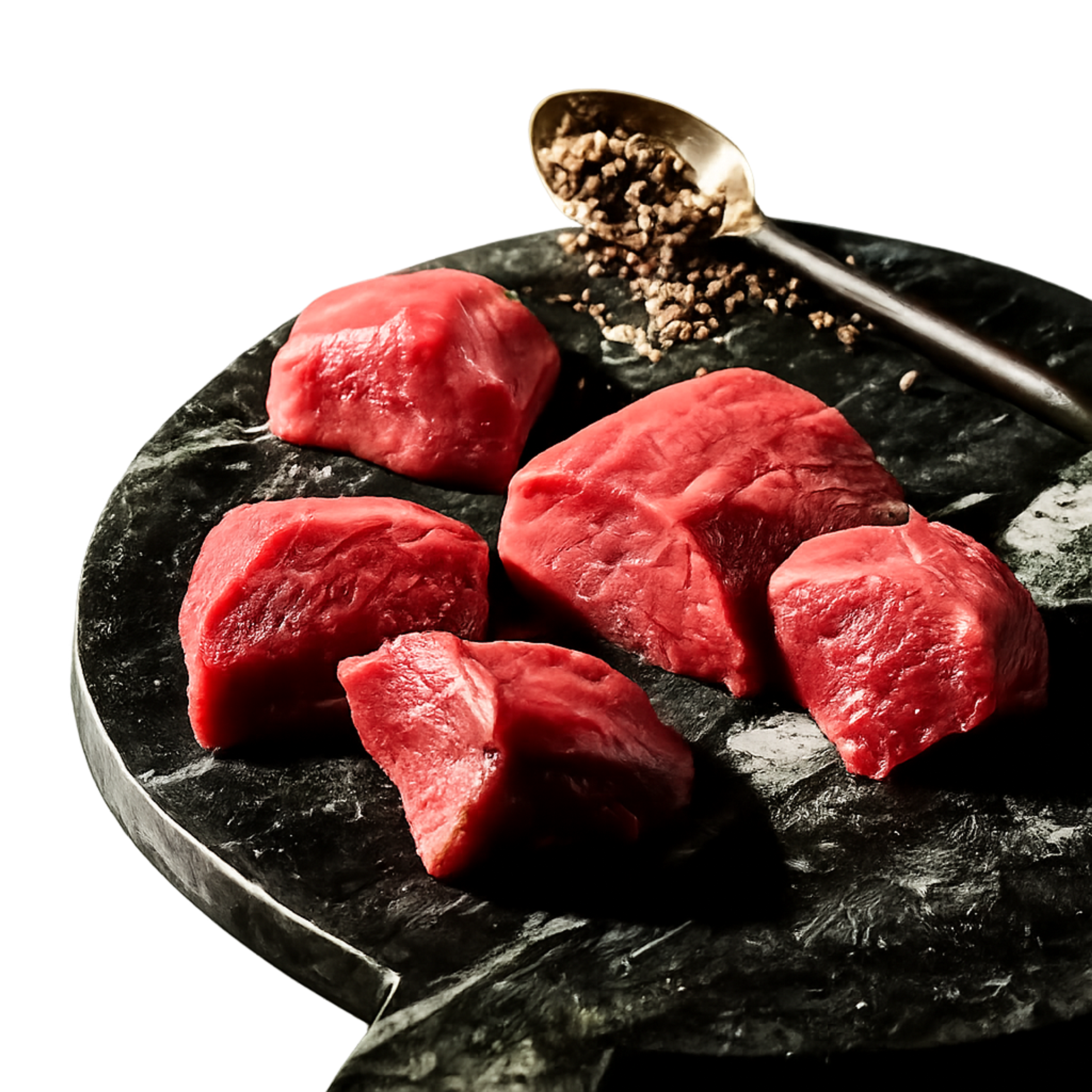 Raw beef chunks on a dark cutting board with a spoon of ground pepper.