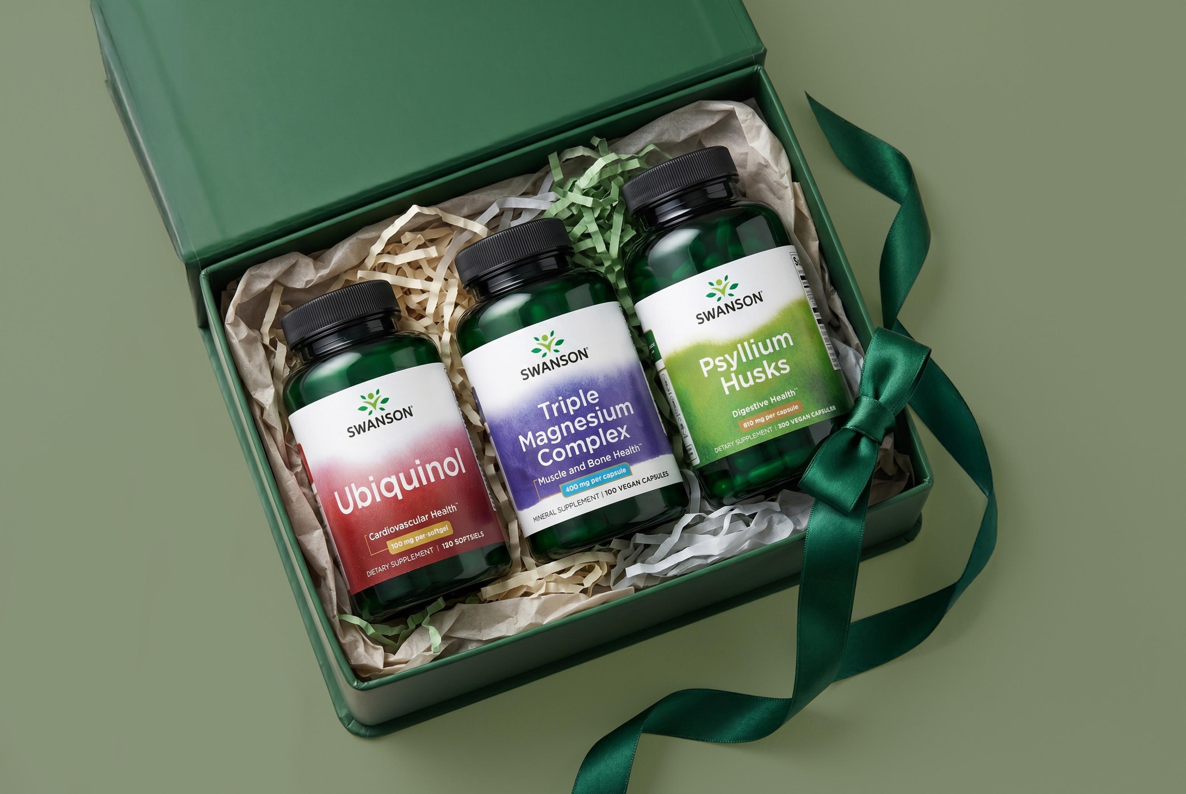 Three Swanson supplement bottles (Ubiquinol, Triple Magnesium Complex, Psyllium Husks) in an open green gift box with a matching ribbon.
