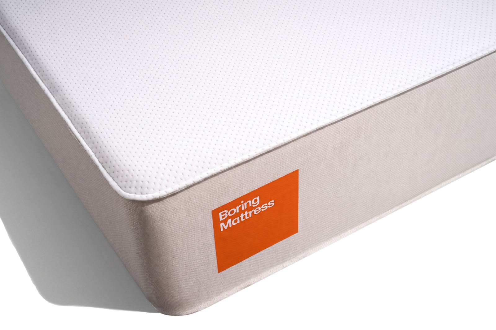 A white and beige mattress with an orange label on the side that reads "Boring Mattress".
