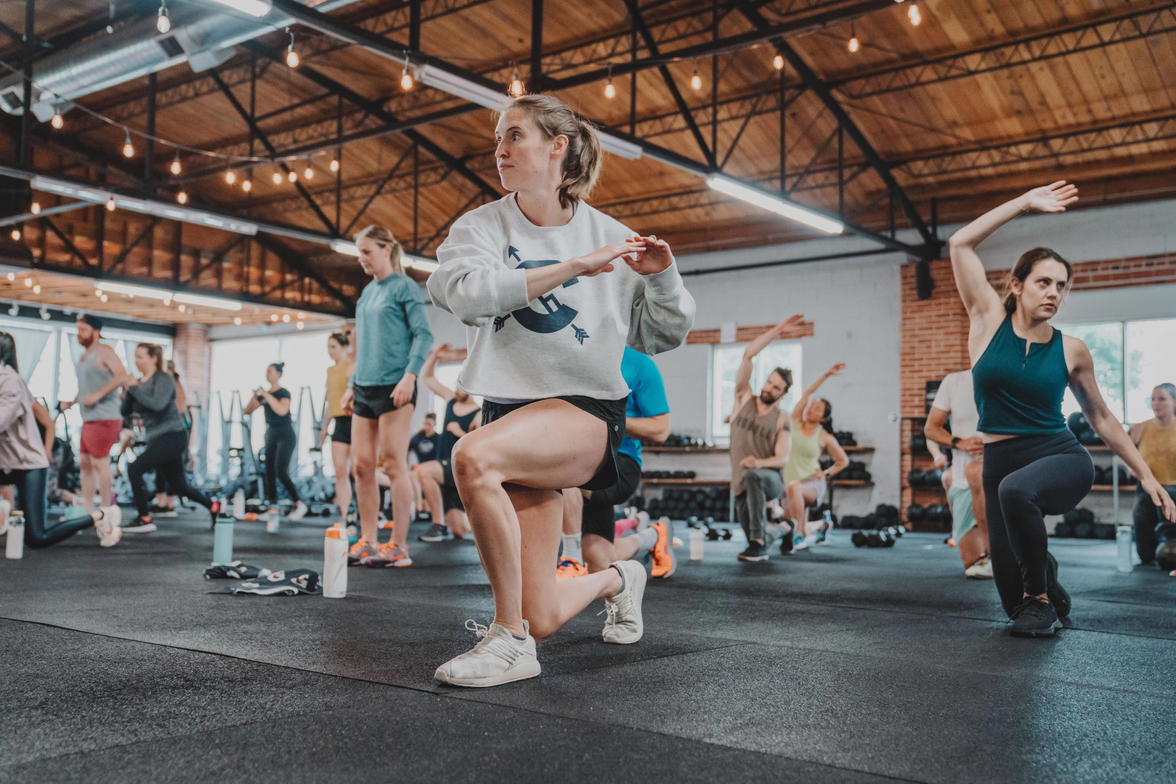 A group of people performing lunges and other exercises in a fitness class.