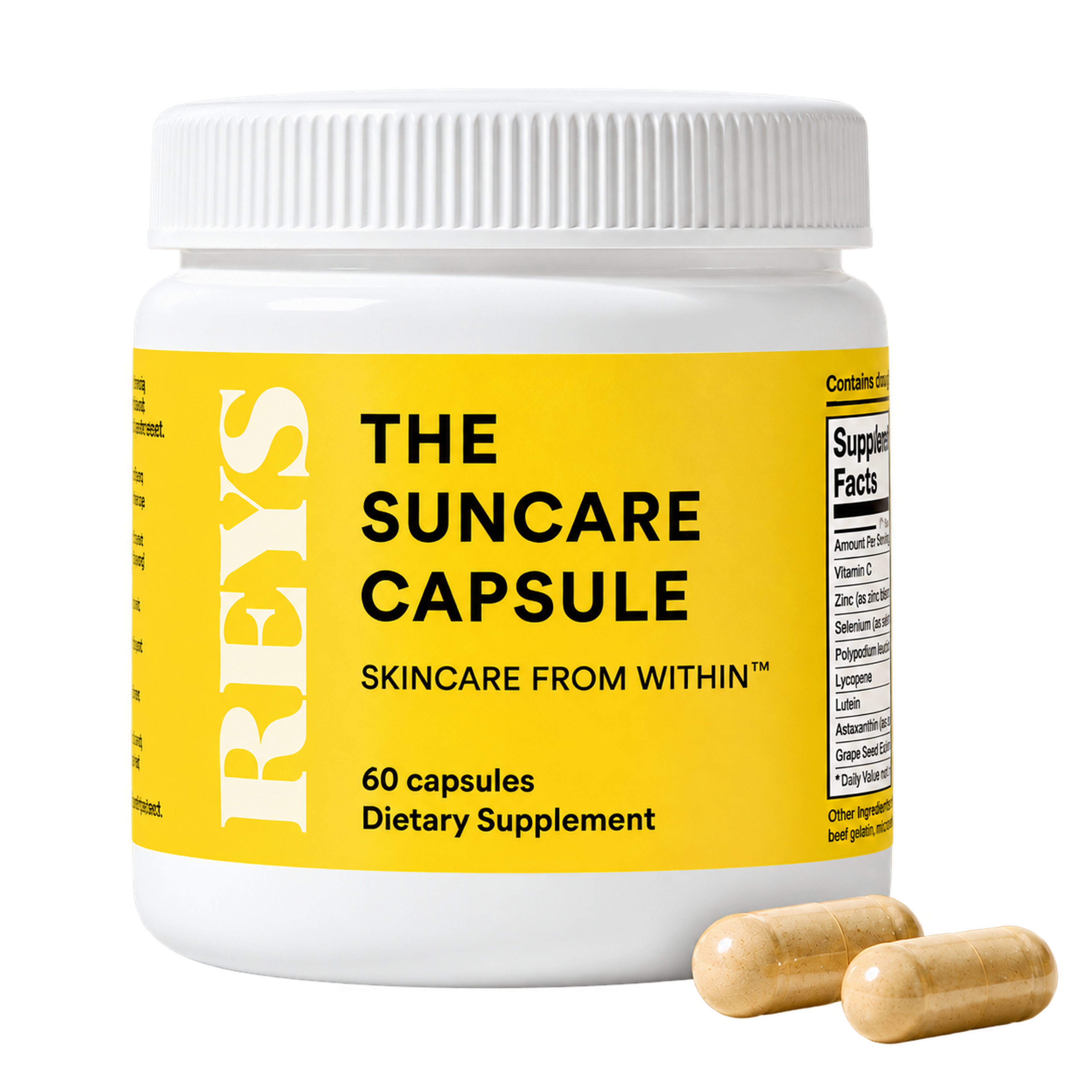 A white bottle of REYS The Suncare Capsule dietary supplement with a yellow label, and two light brown capsules in front.