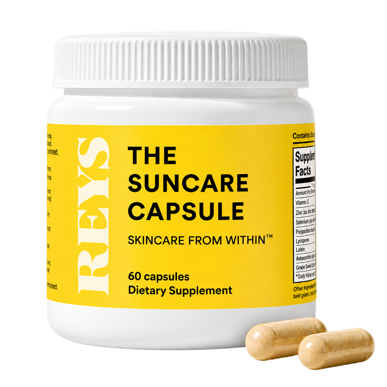 A white bottle of REYS The Suncare Capsule dietary supplement with a yellow label, and two light brown capsules in front.