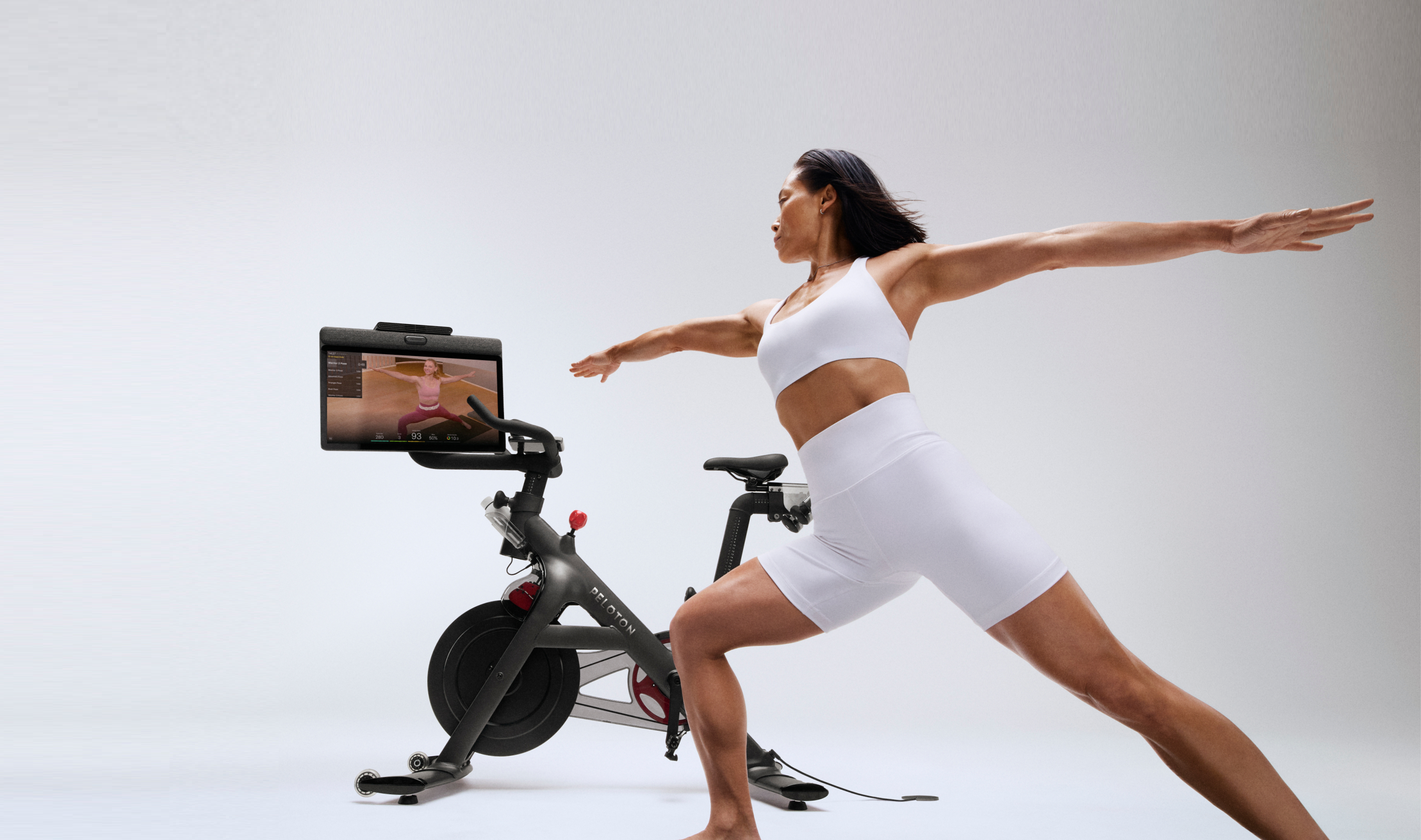 Woman working out next to Peloton Bike+ using Peloton guided program
