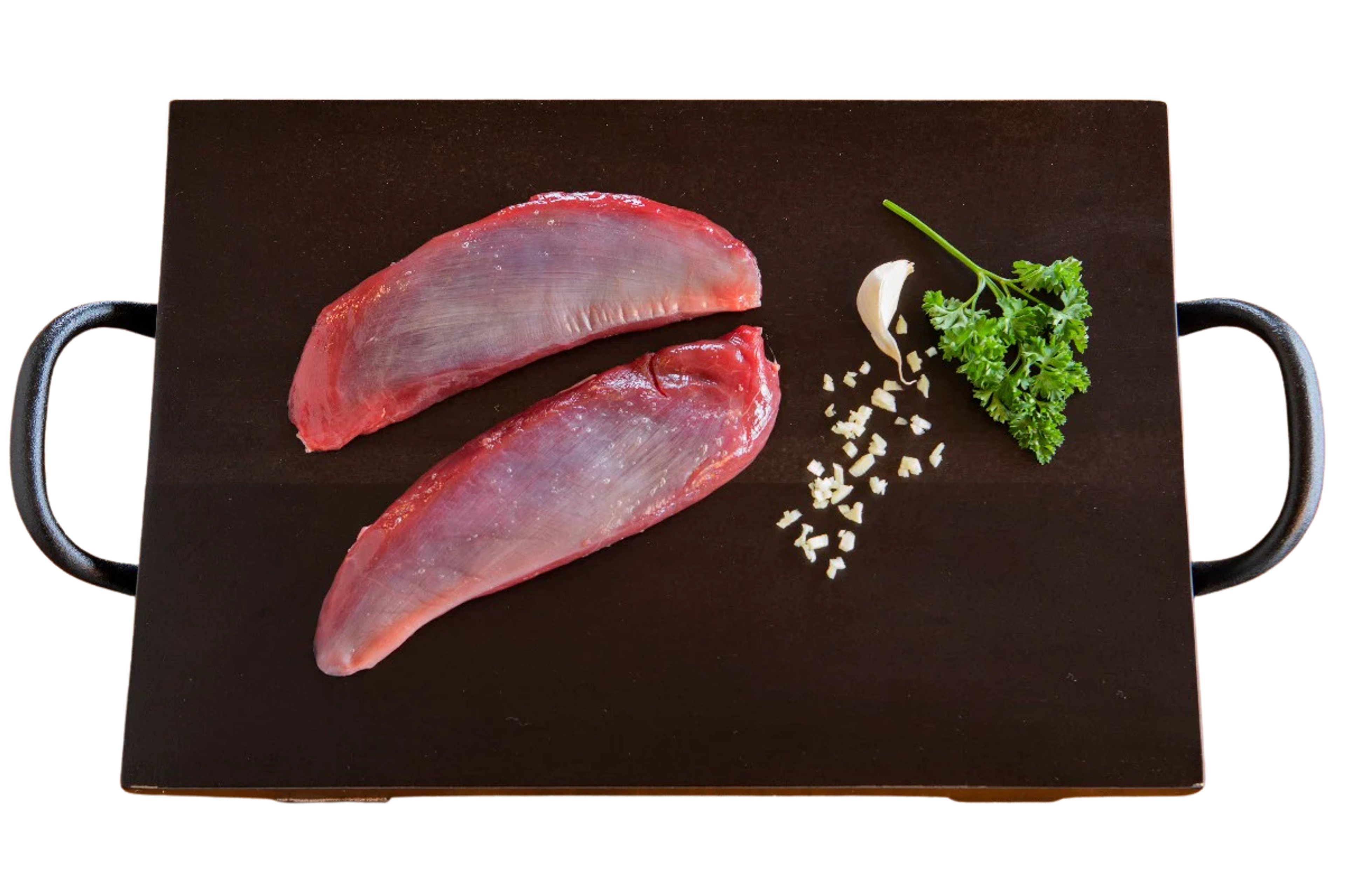 Two raw duck breasts, garlic, and parsley on a dark cutting board.