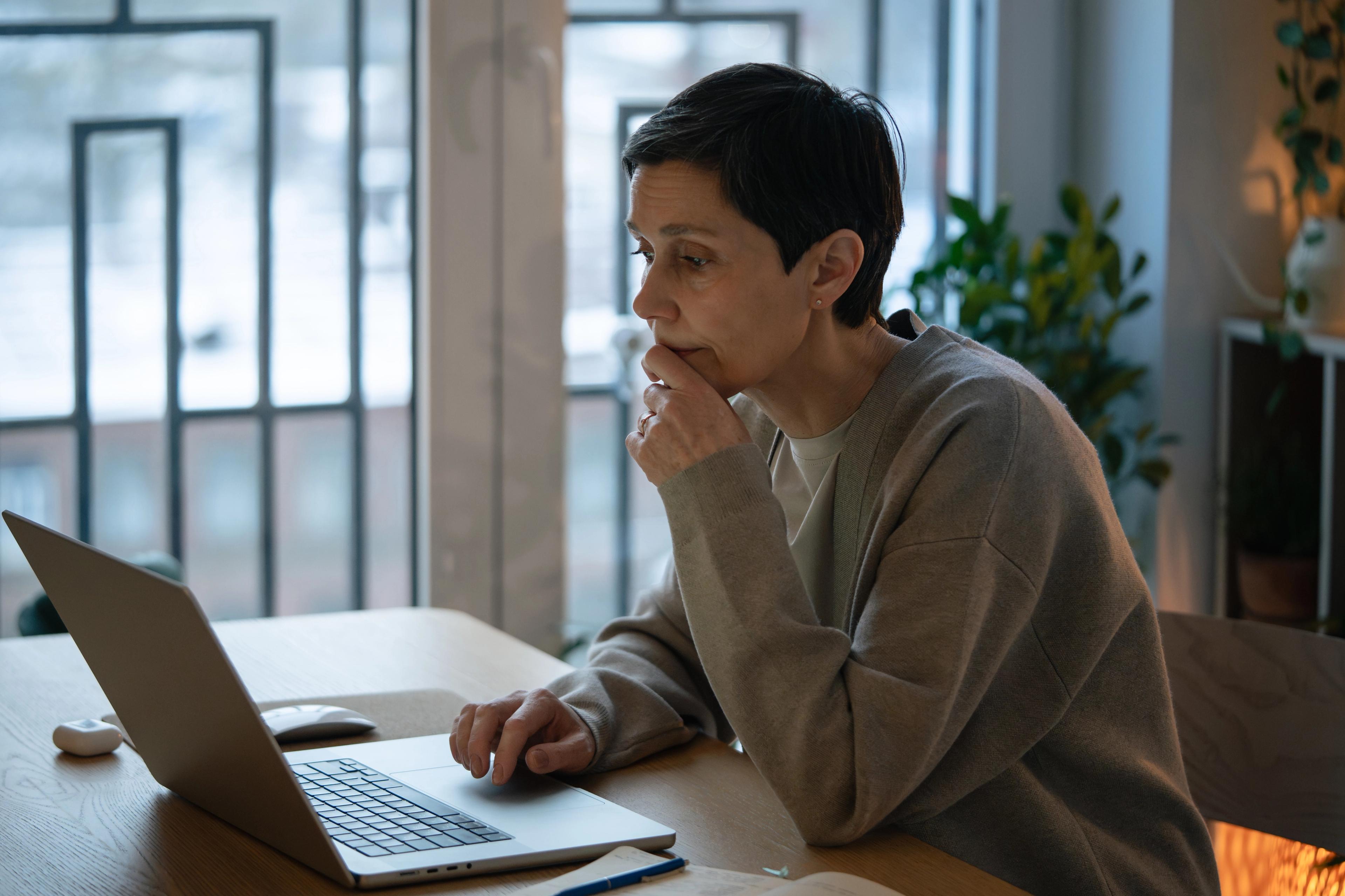 Woman looking at laptop considering open enrollment decisions
