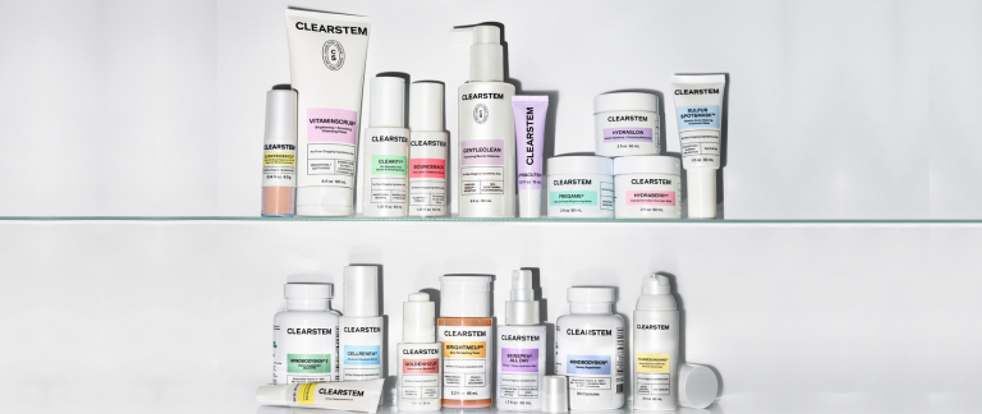 An assortment of CLEARSTEM skincare products with white packaging and colorful labels displayed on two shelves.