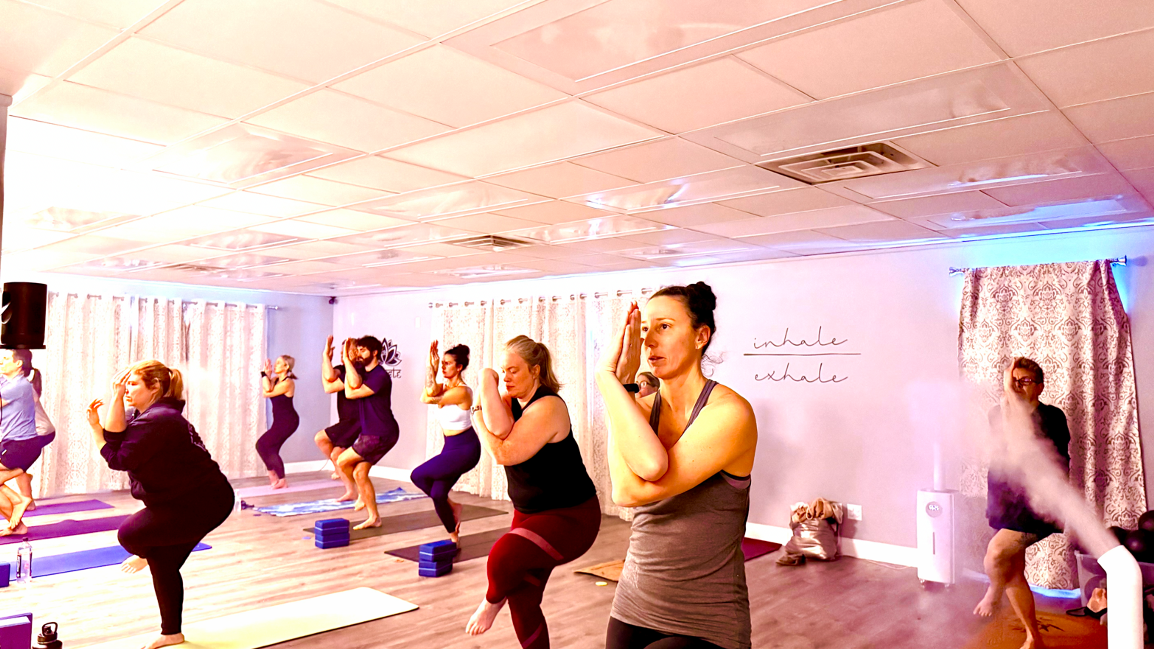 A group of people in a yoga studio performing Eagle Pose.