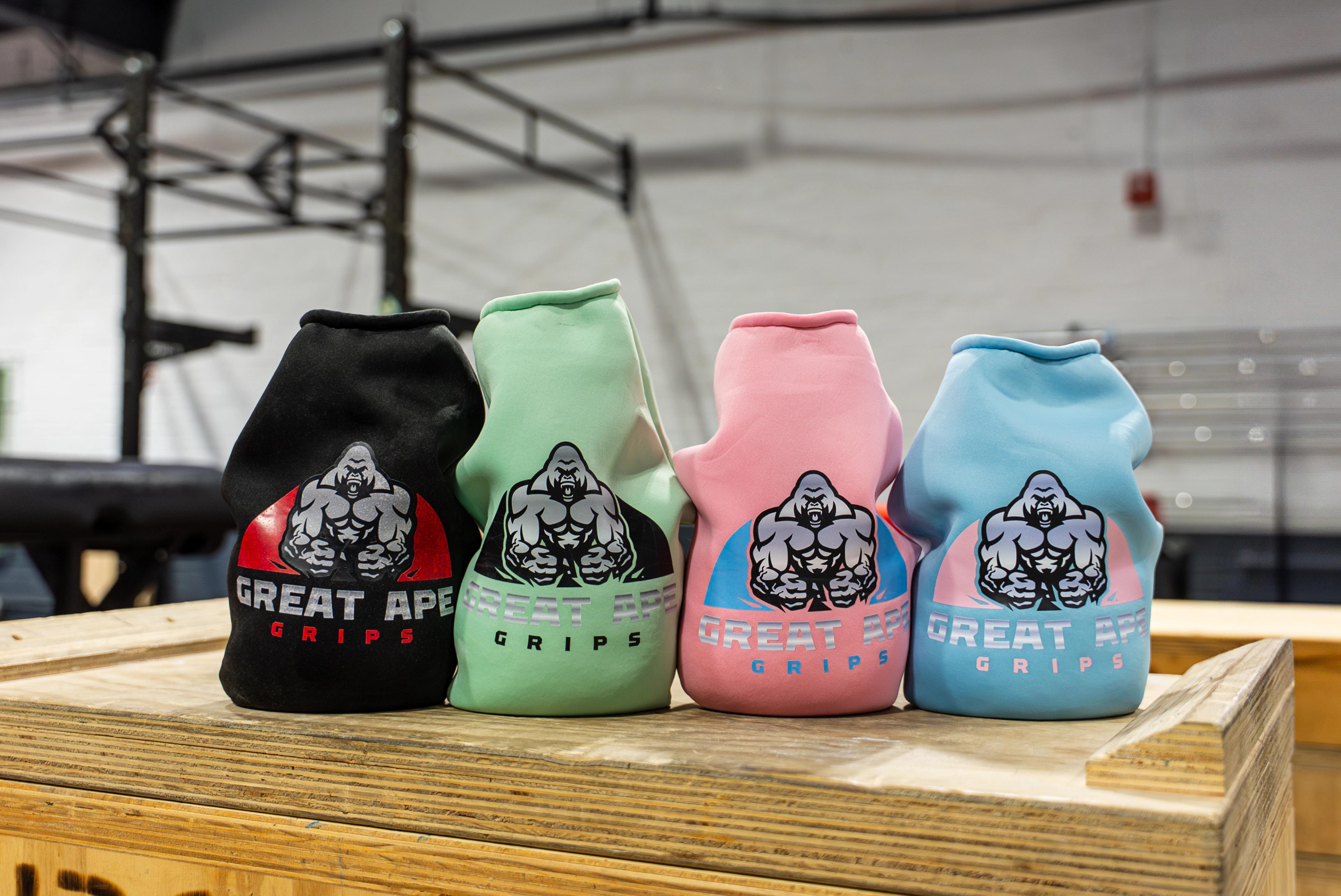 Four Great Ape Grips in black, mint, pink, and blue on a wooden box in a gym.