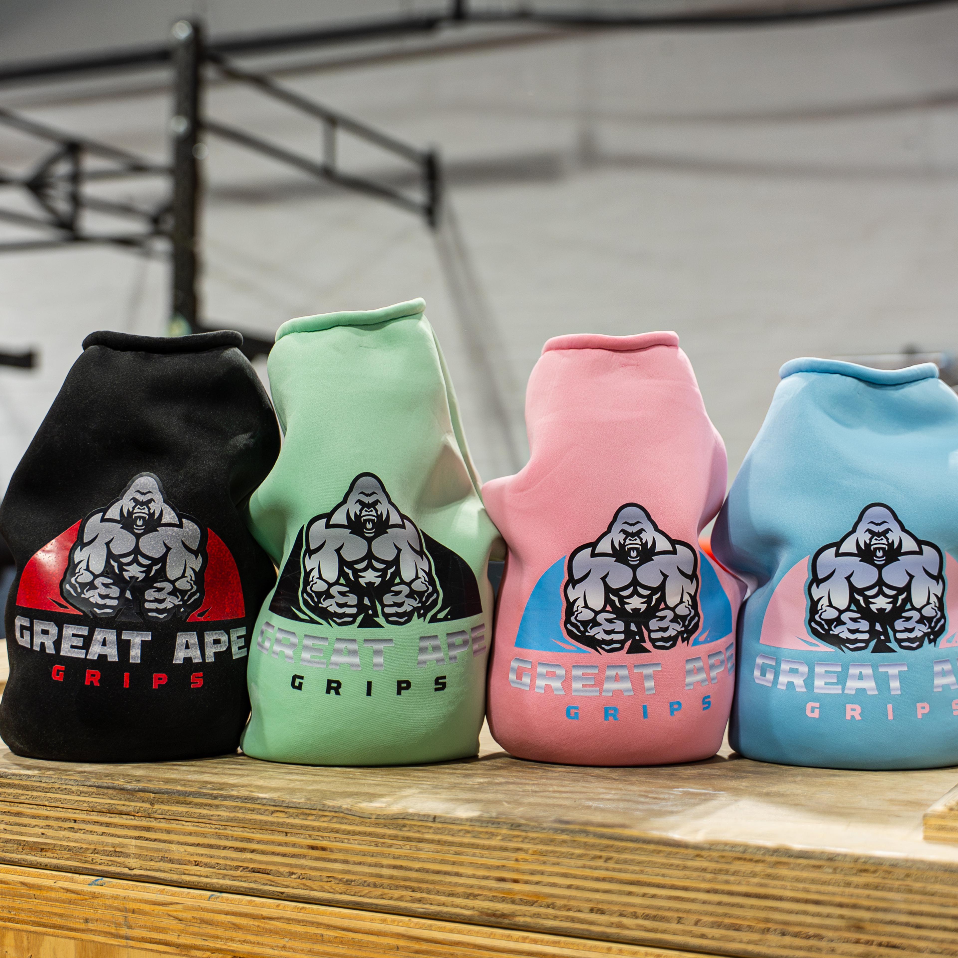 Four Great Ape Grips in black, mint, pink, and blue on a wooden box in a gym.
