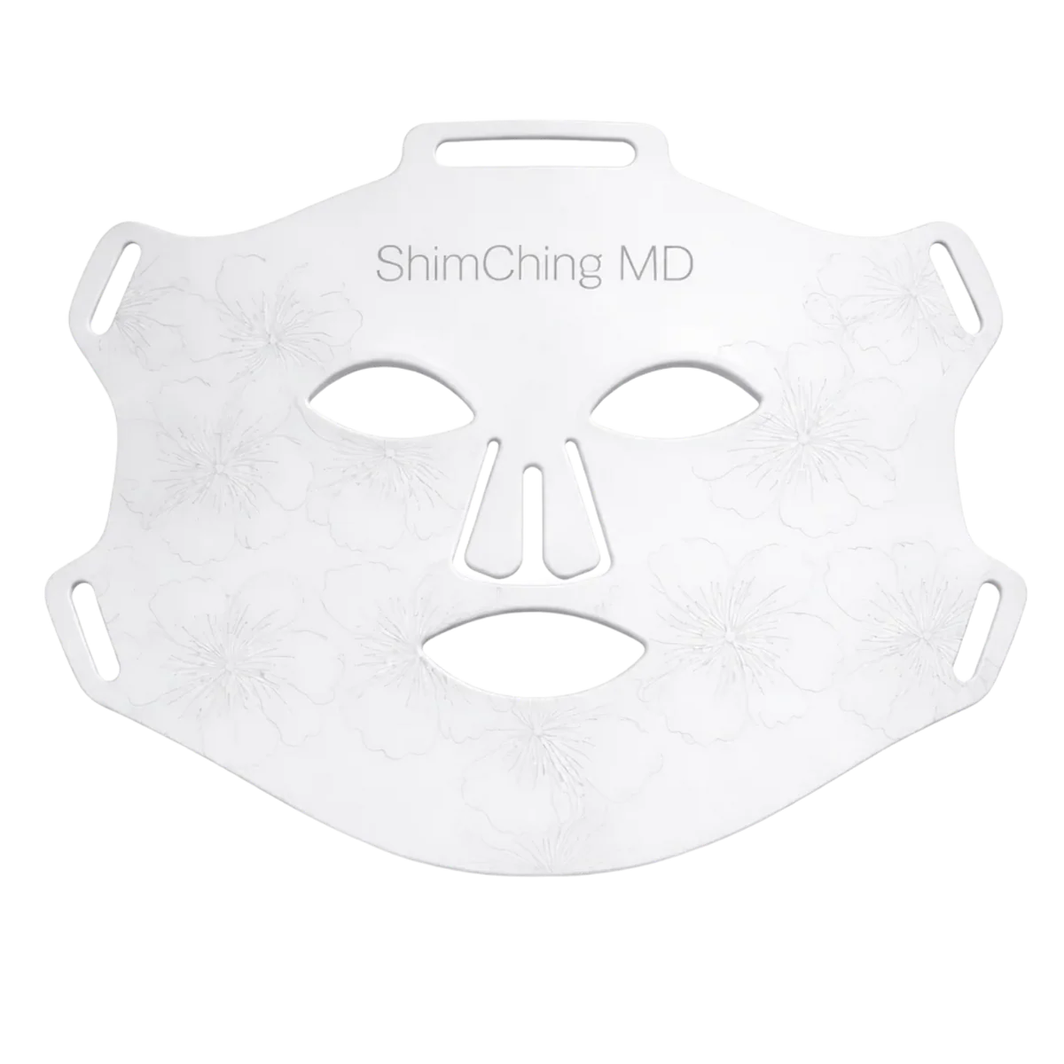 A white reusable face mask with eye, nose, and mouth cutouts, 'ShimChing MD' text, and embossed floral patterns.