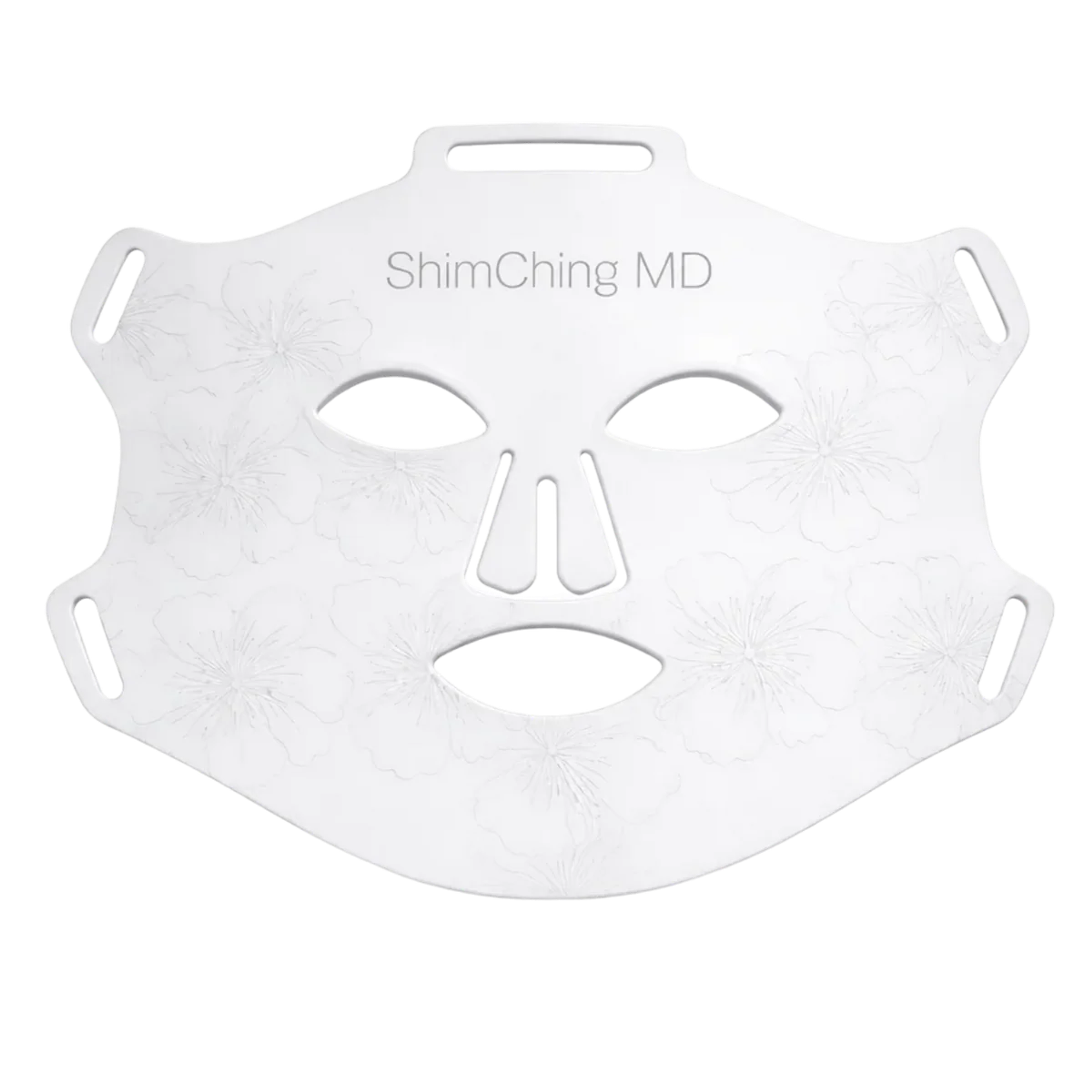 A white reusable face mask with eye, nose, and mouth cutouts, 'ShimChing MD' text, and embossed floral patterns.