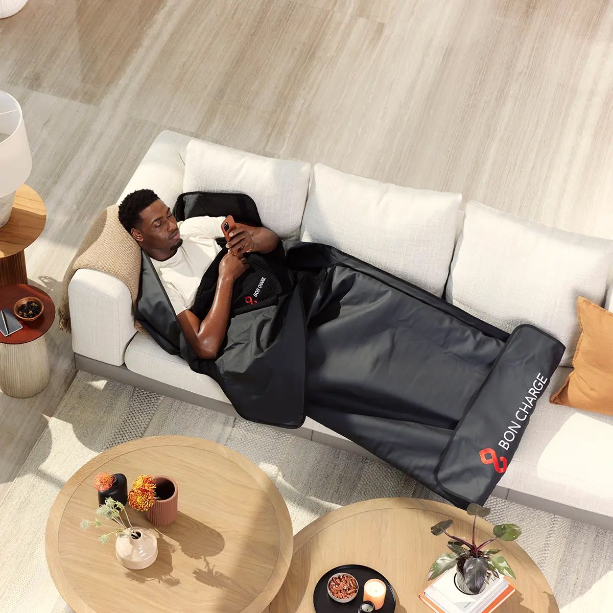 Man using Bon Charge red light therapy blanket while laying on couch