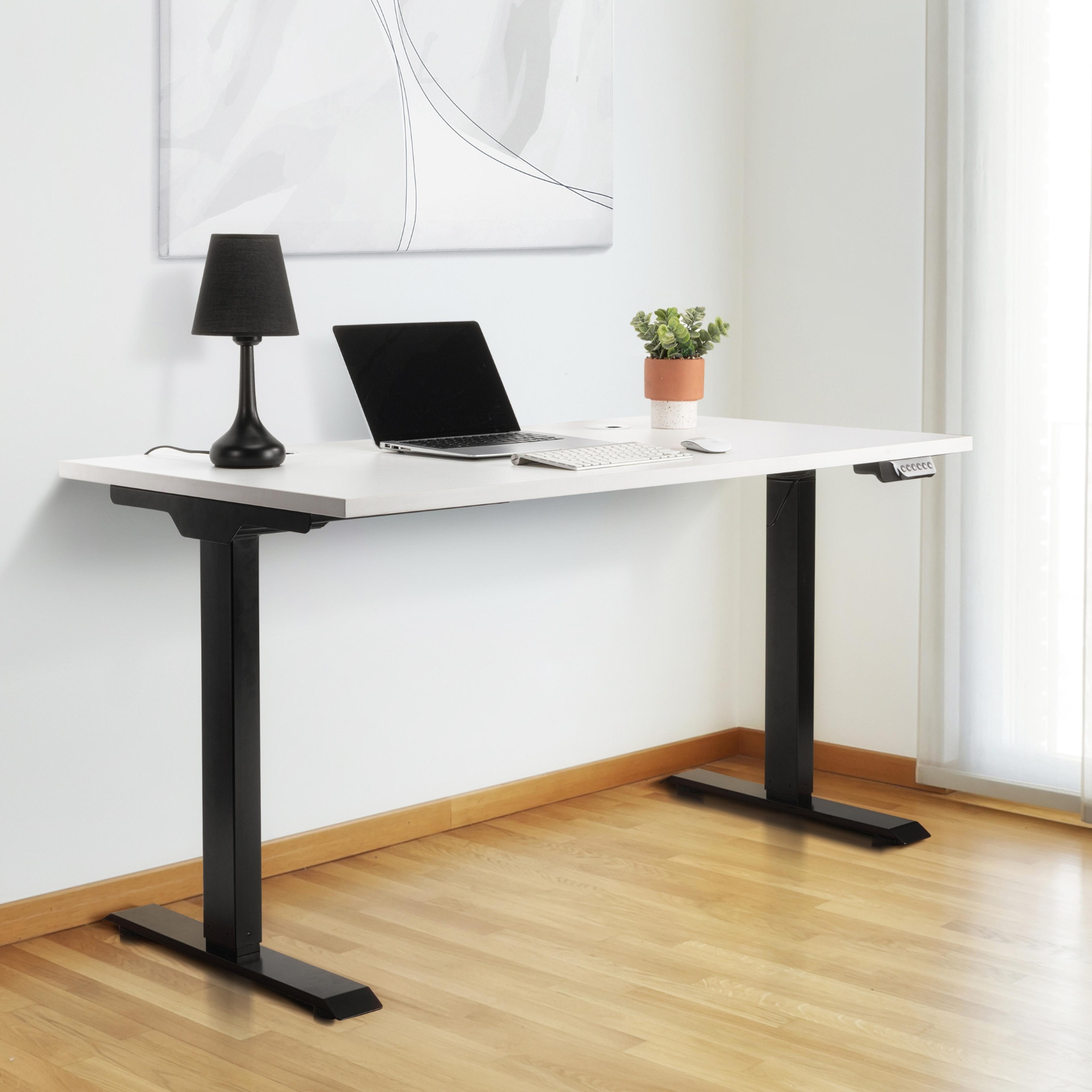 White standing desk with black legs, laptop, black lamp, and potted plant.