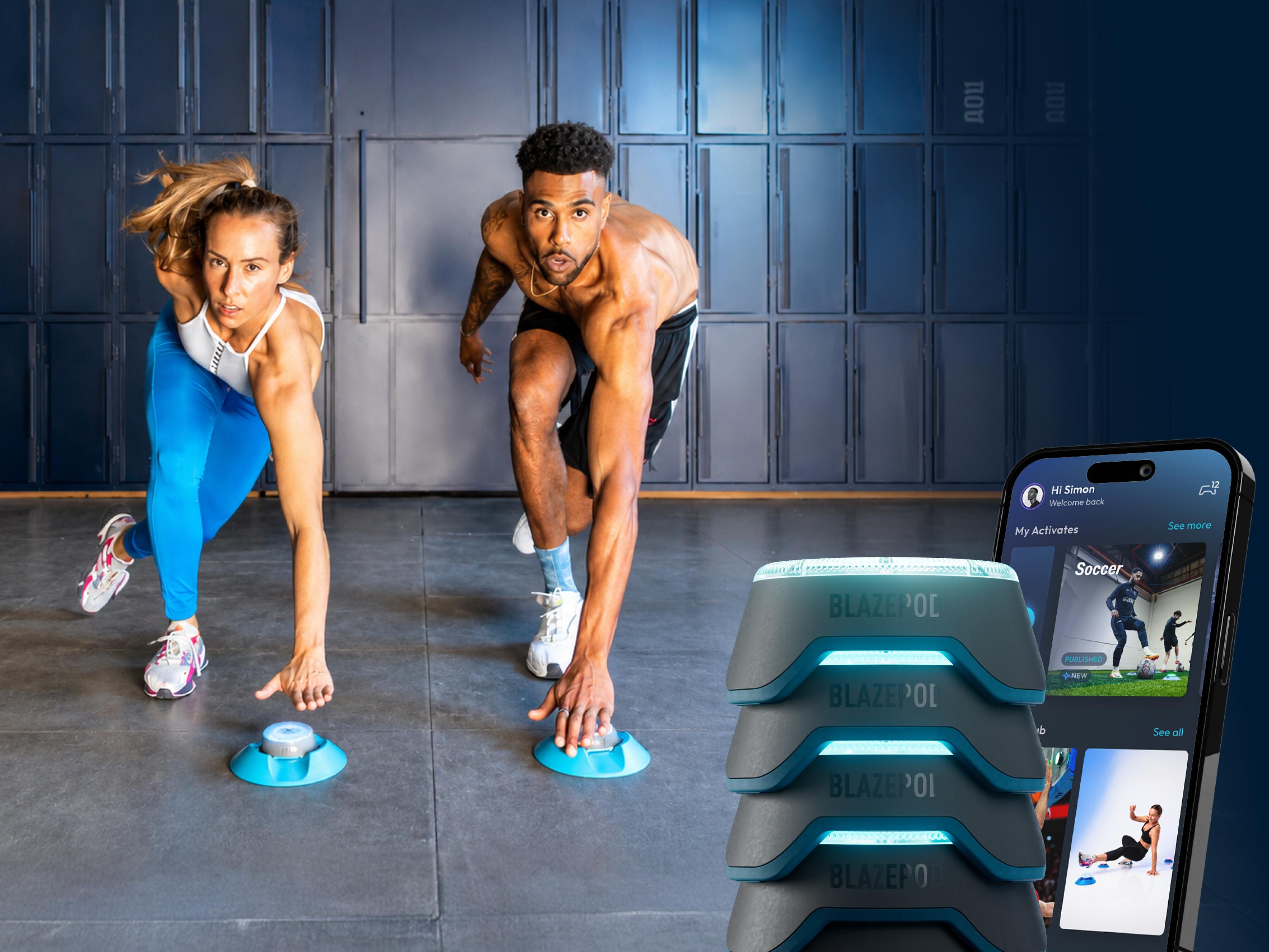 Two athletes touching glowing Blazepods on the floor during a workout, with a stack of pods and the Blazepod app on a smartphone.
