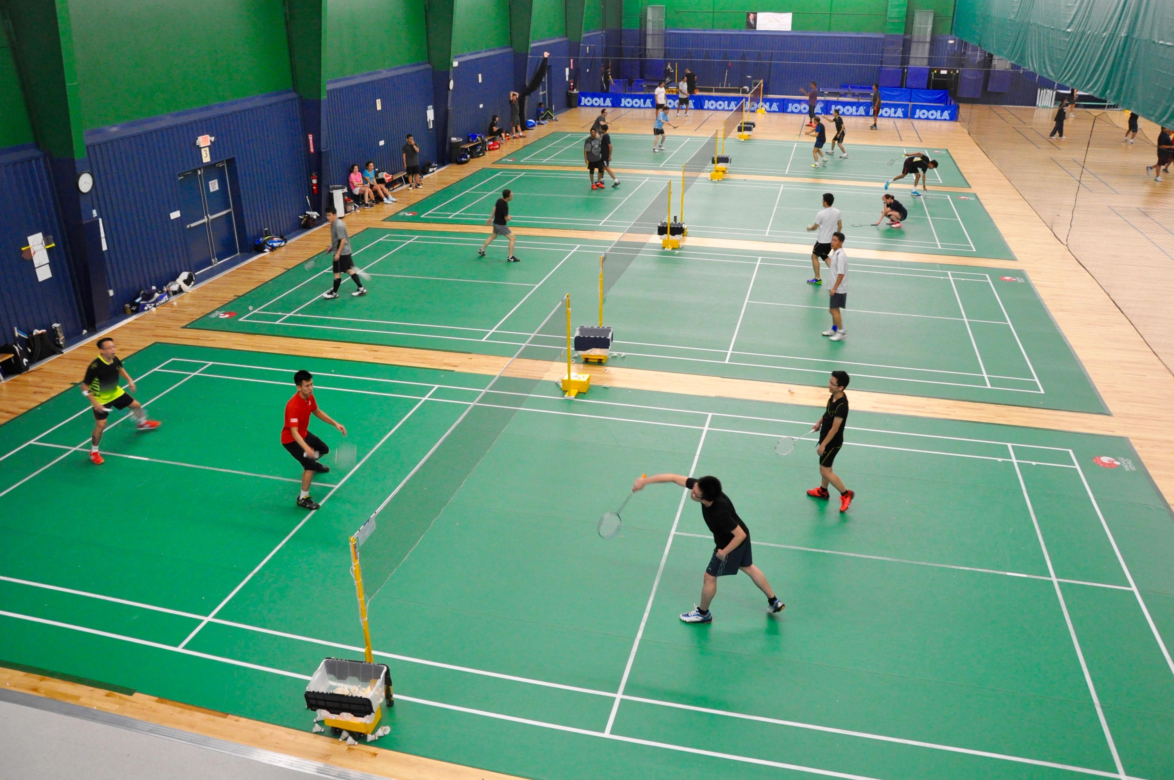 People playing badminton on multiple courts in an indoor facility.