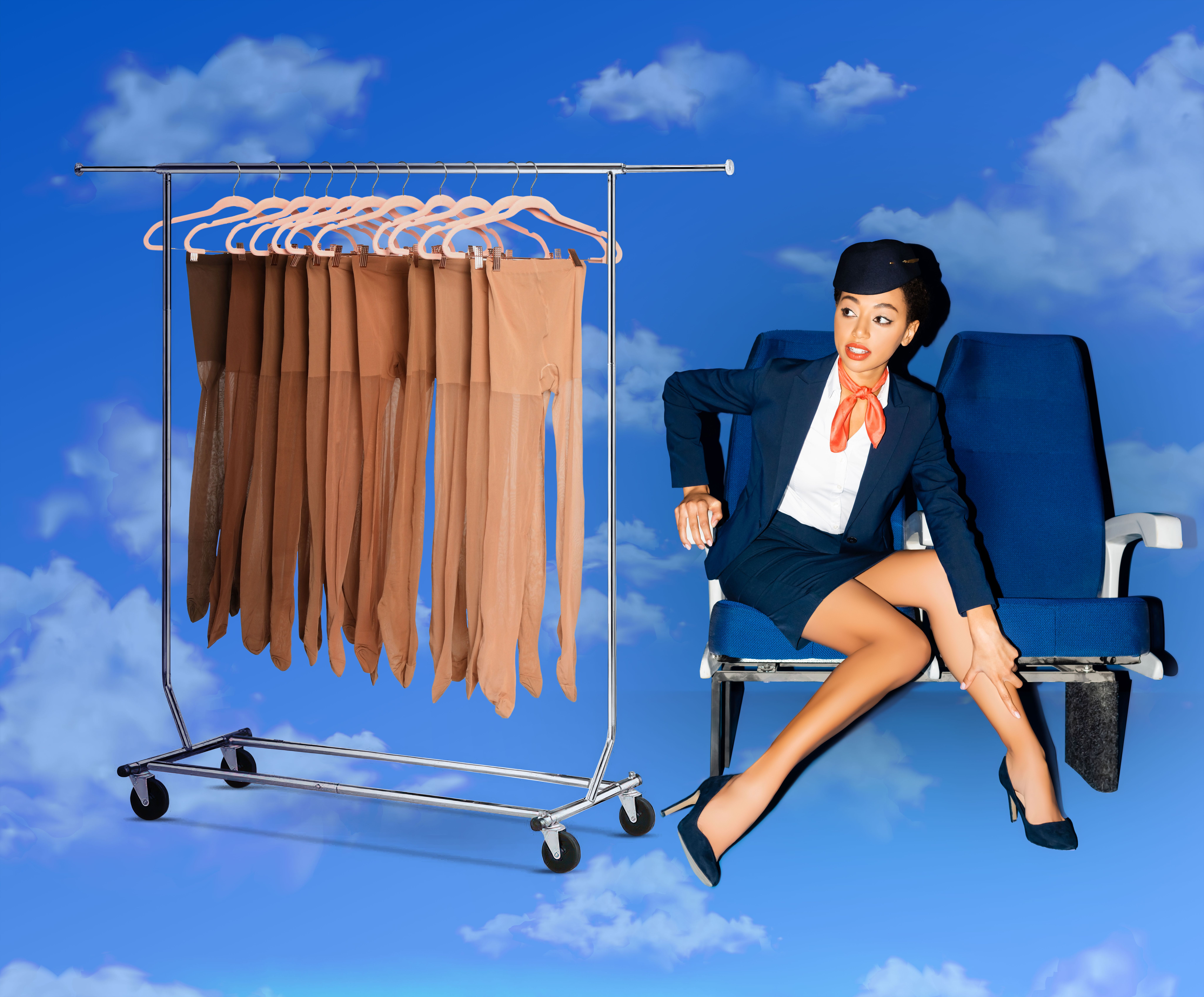 A flight attendant adjusts her leg next to a rack of pantyhose, sitting on airplane seats against a cloudy sky.