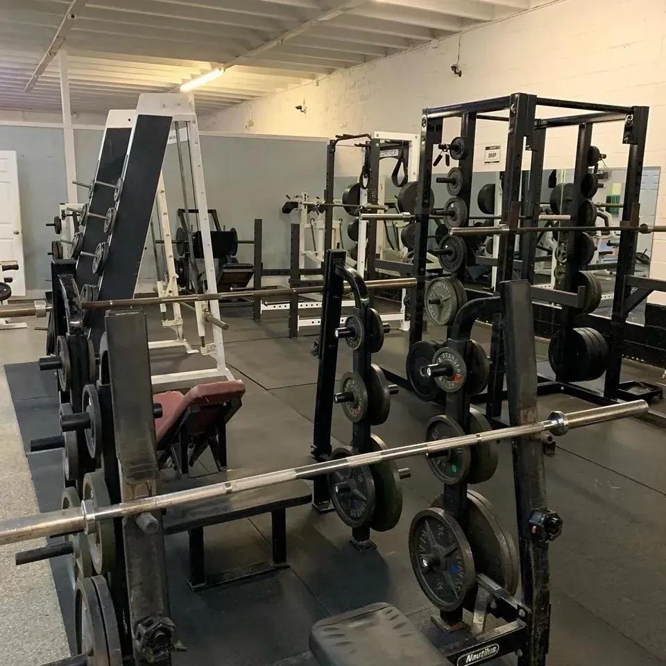 An empty gym with weight racks, barbells, and numerous weight plates.