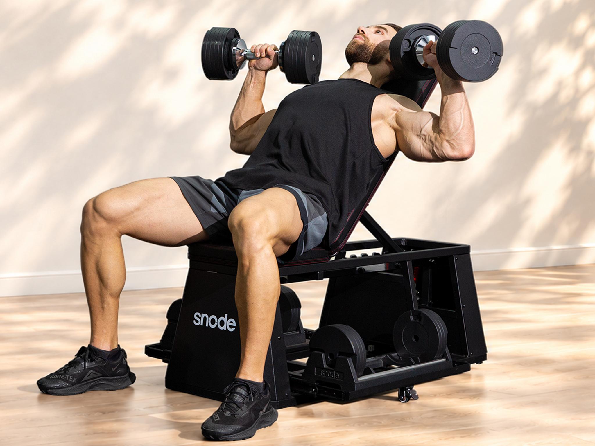 Muscular man doing incline dumbbell presses on a black Snod bench.